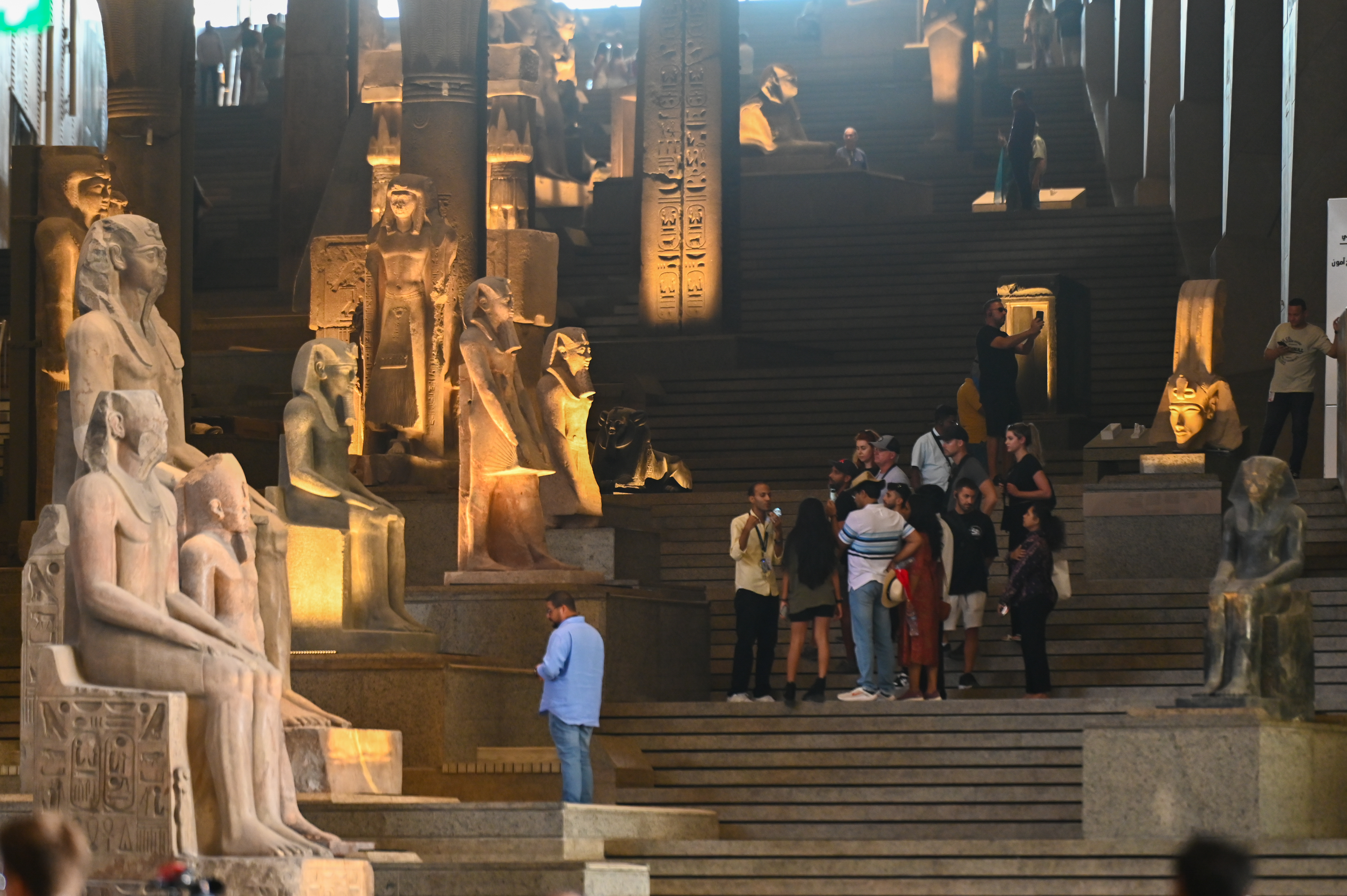 GIZA, EGYPT - OCTOBER 15: Visitors walk past ancient Egyptian colossal statues along the Grand Staircase at the Grand Egyptian Museum during partial trial operation on October 15, 2024 in Giza, Egypt. With 872,000 square-feet of floorspace, the Grand Egyptian Museum is the largest archaeological museum in the world. (Photo by Sayed Hassan/Getty Images)