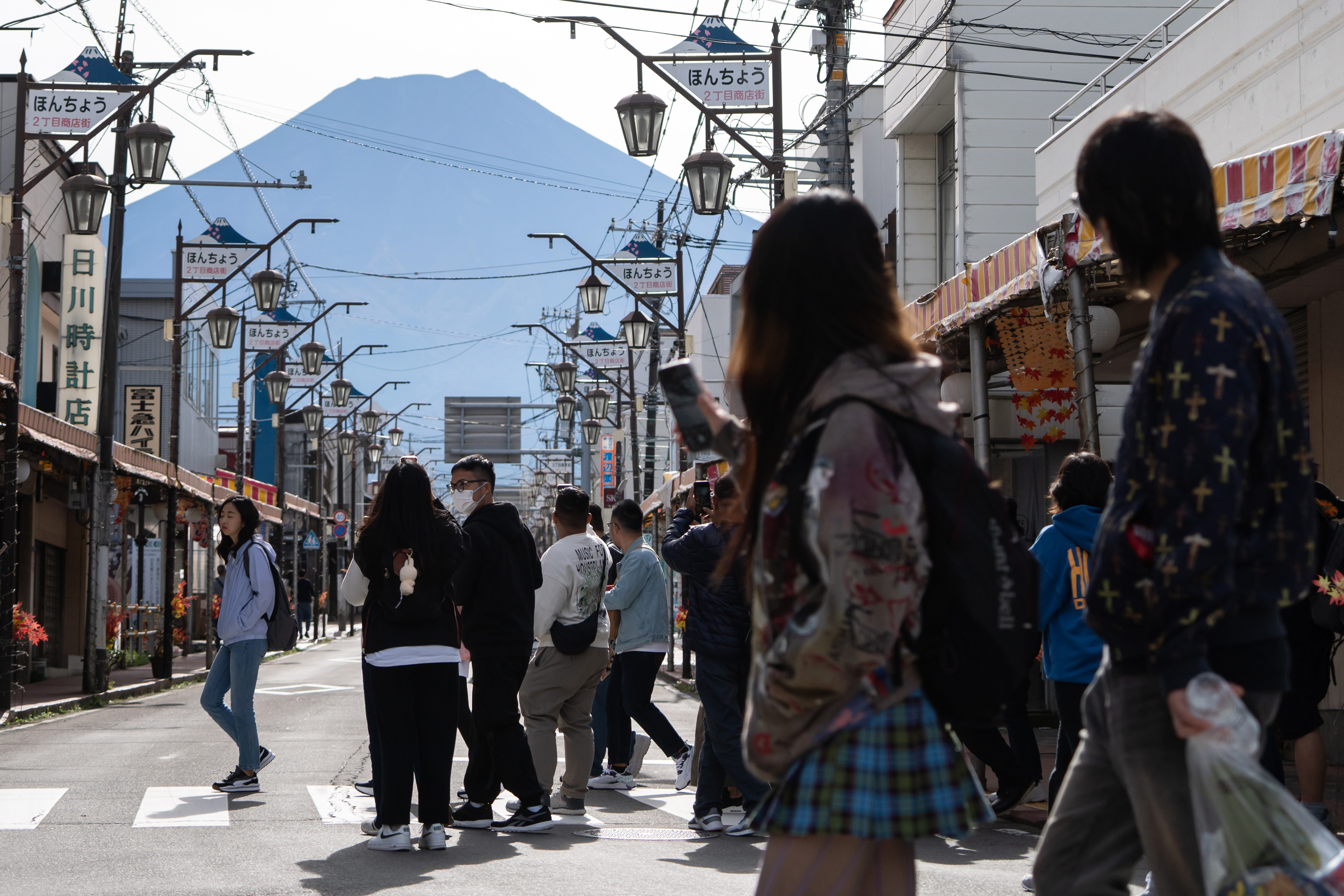 Tourists cross a road leading towards Mount Fuji.