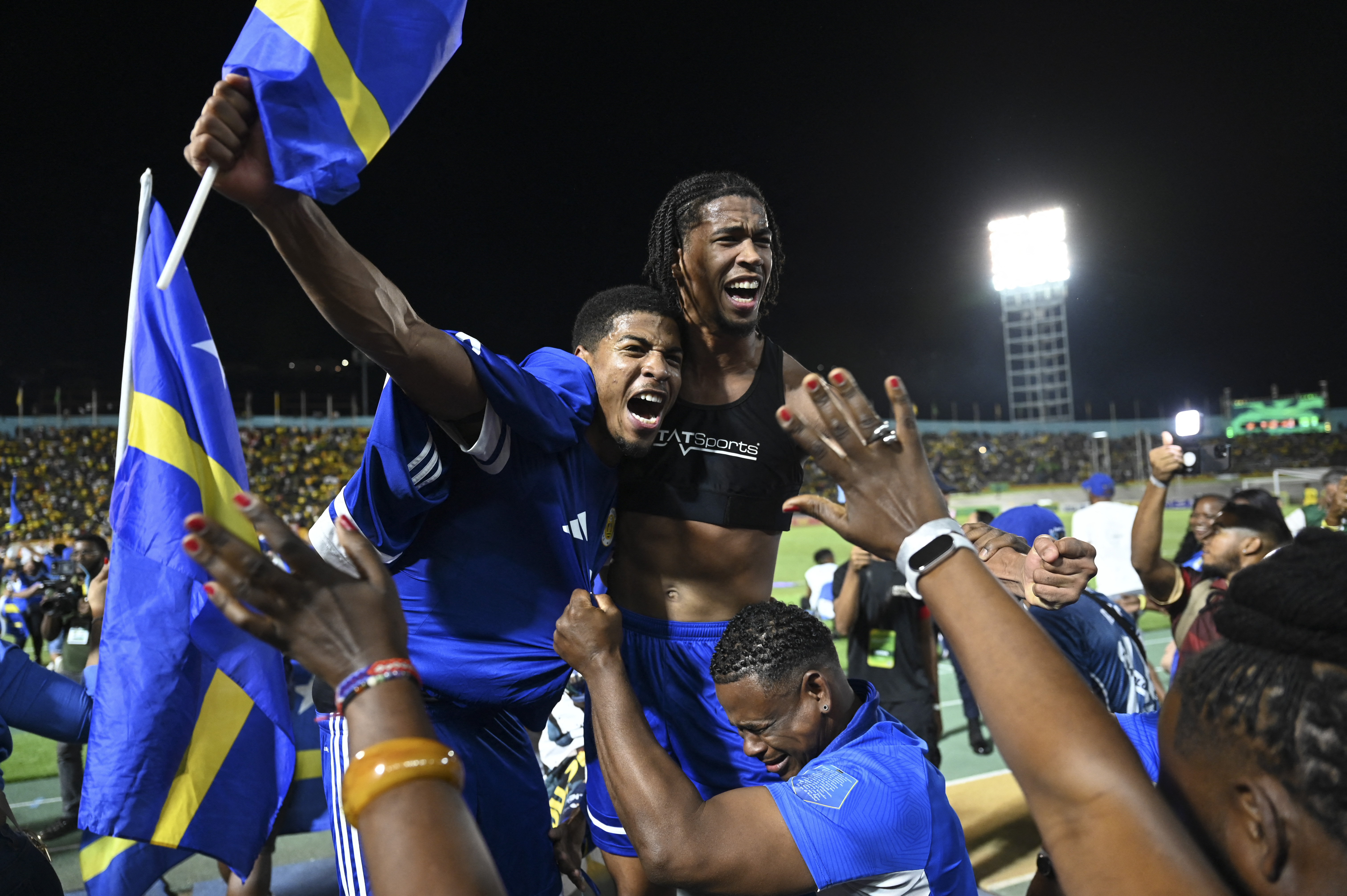 TOPSHOT - Curaçao players and fans celebrate World Cup 2026 qualification after a 0-0 draw with Jamaica at the National Stadium in Kingston, Jamaica on November 18, 2025.