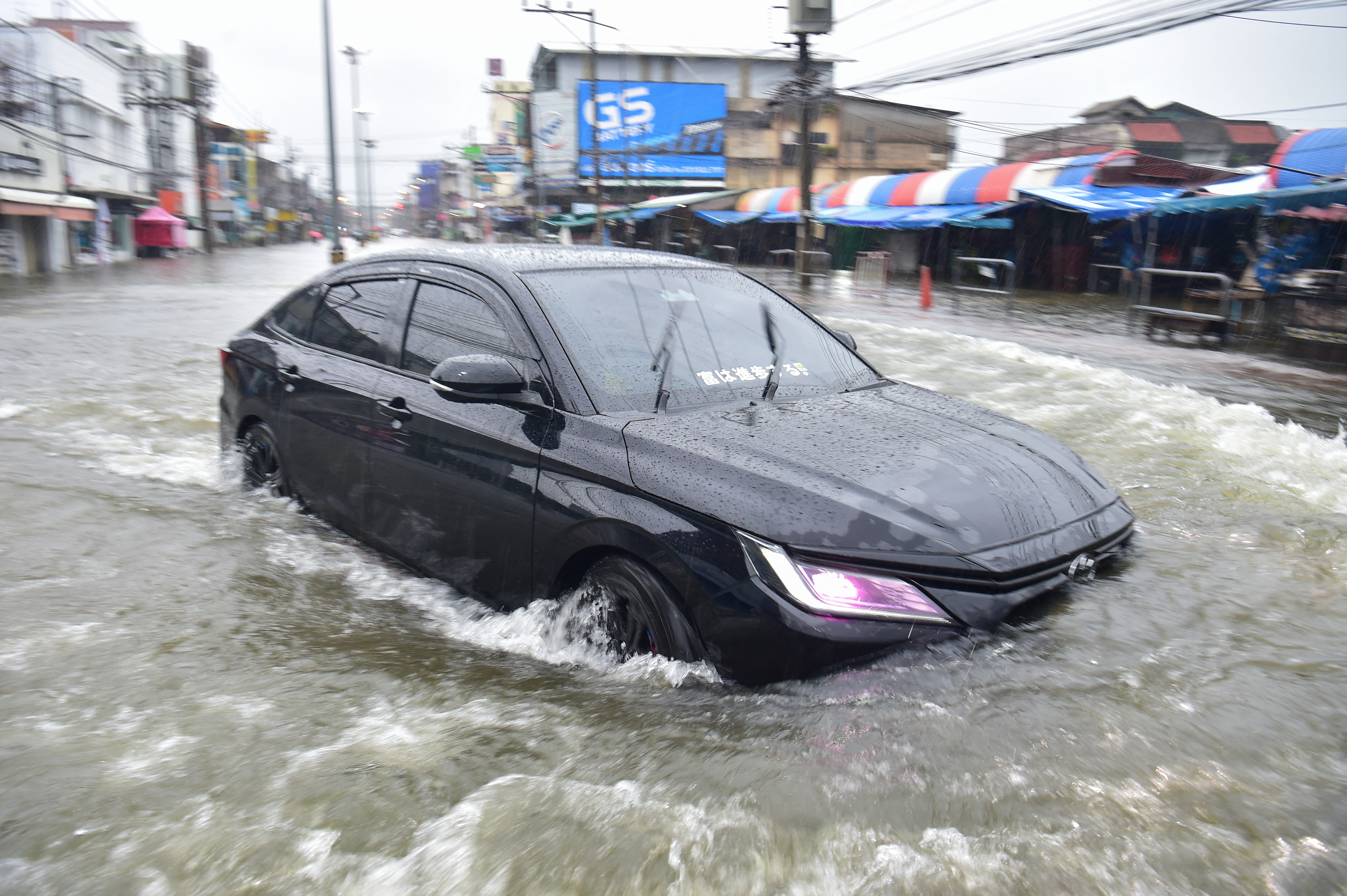 A motorist drives his car through floodwaters following heavy rain in Thailand's southern province of Narathiwat on November 23, 2025. (Photo by Madaree TOHLALA / AFP)