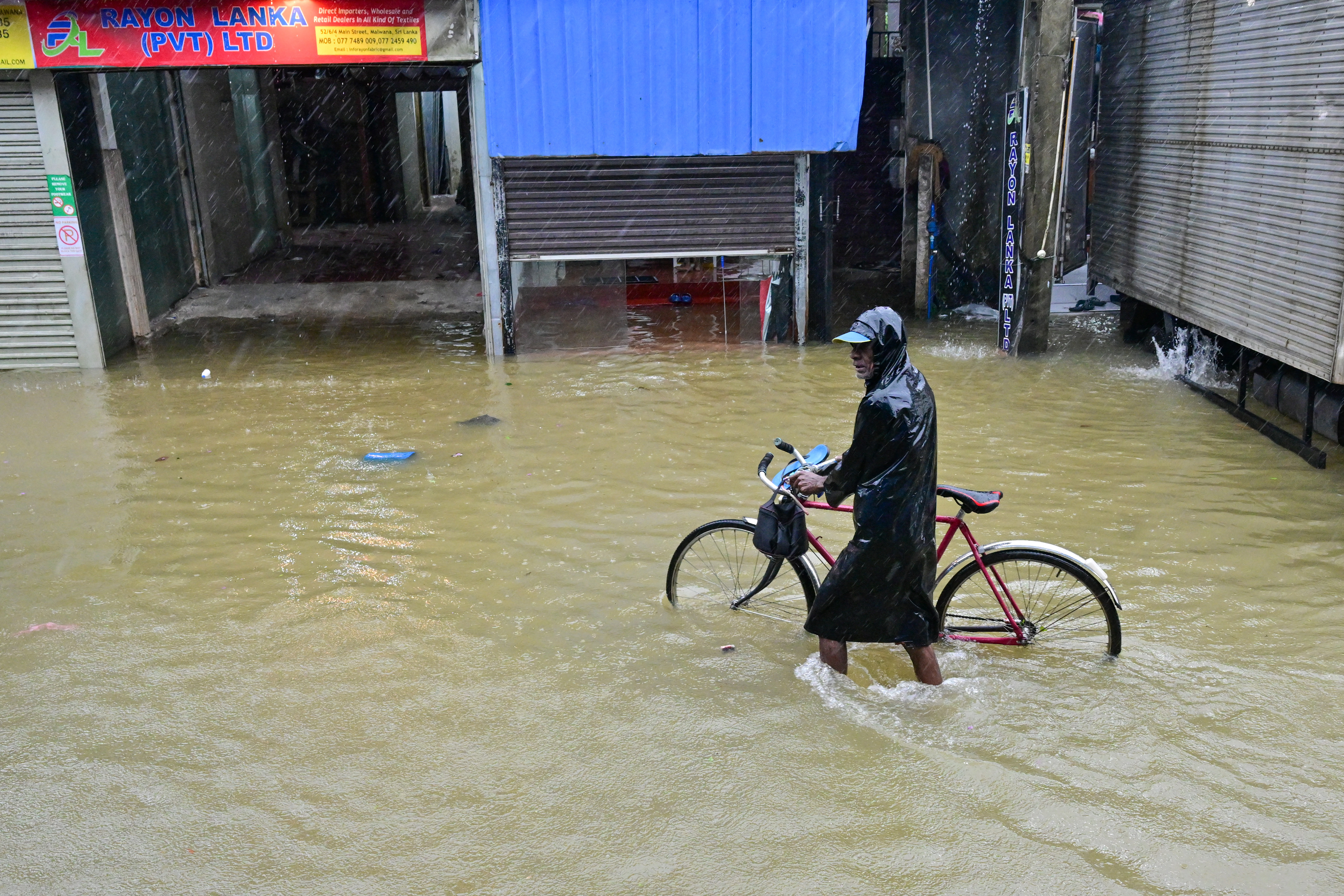 A resident wades through a flooded street after heavy rains.