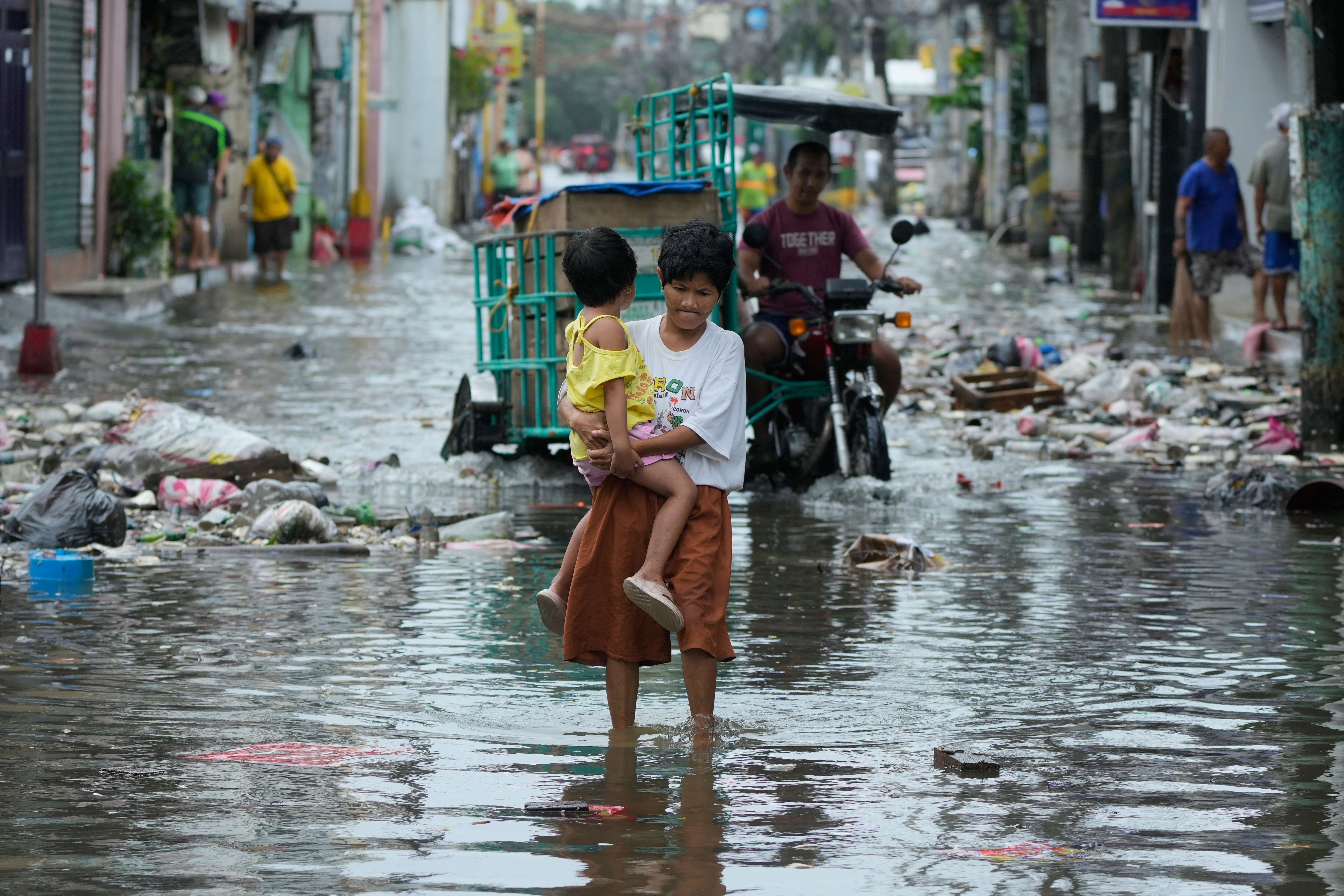A woman and child crosses a flooded street due to Typhoon Fung-wong and high tide in Navotas, Philippines