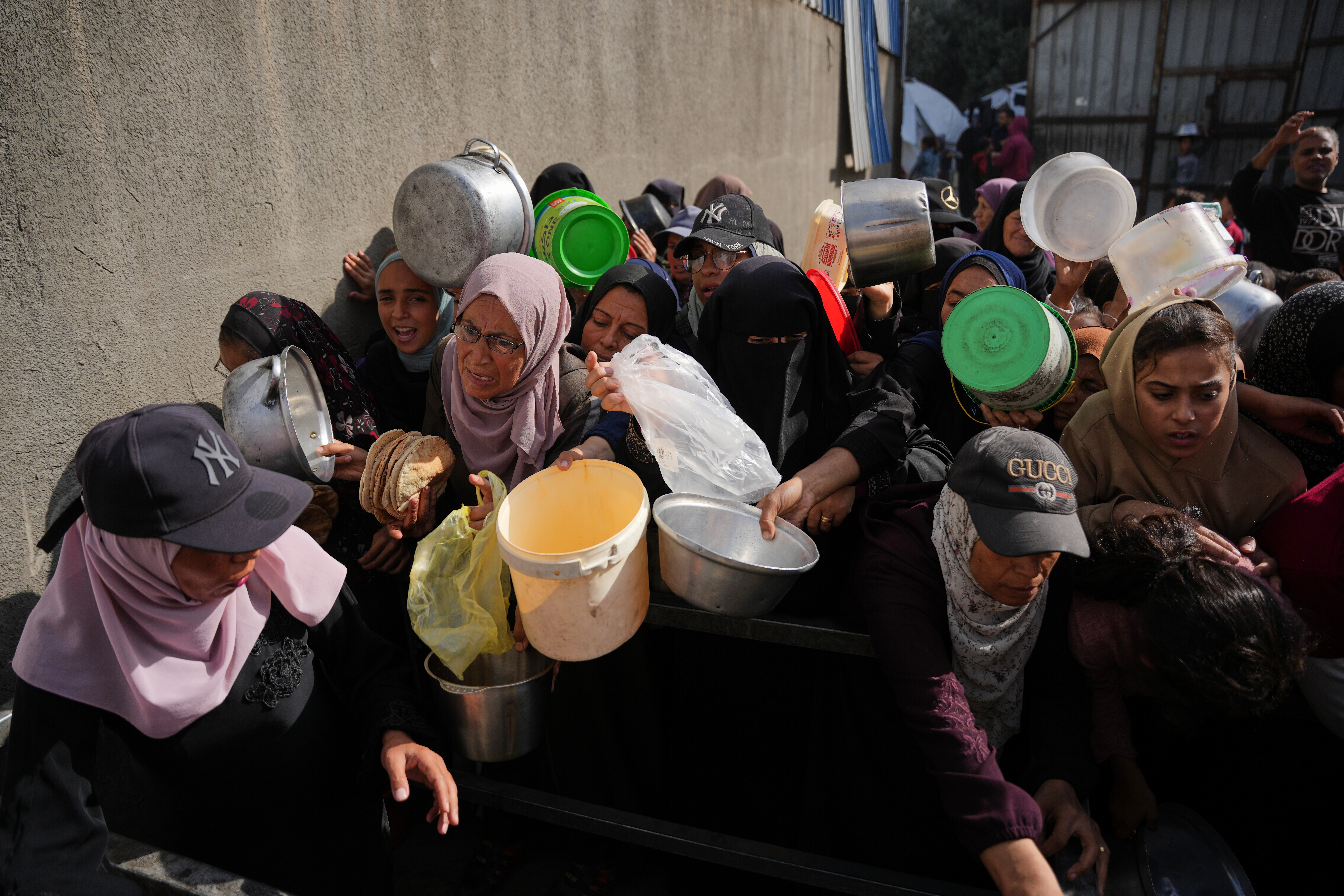 Palestinian women struggle to receive donated food at a community kitchen in Nuseirat, central Gaza Strip, Wednesday, Nov. 19, 2025. (AP Photo/Abdel Kareem Hana)