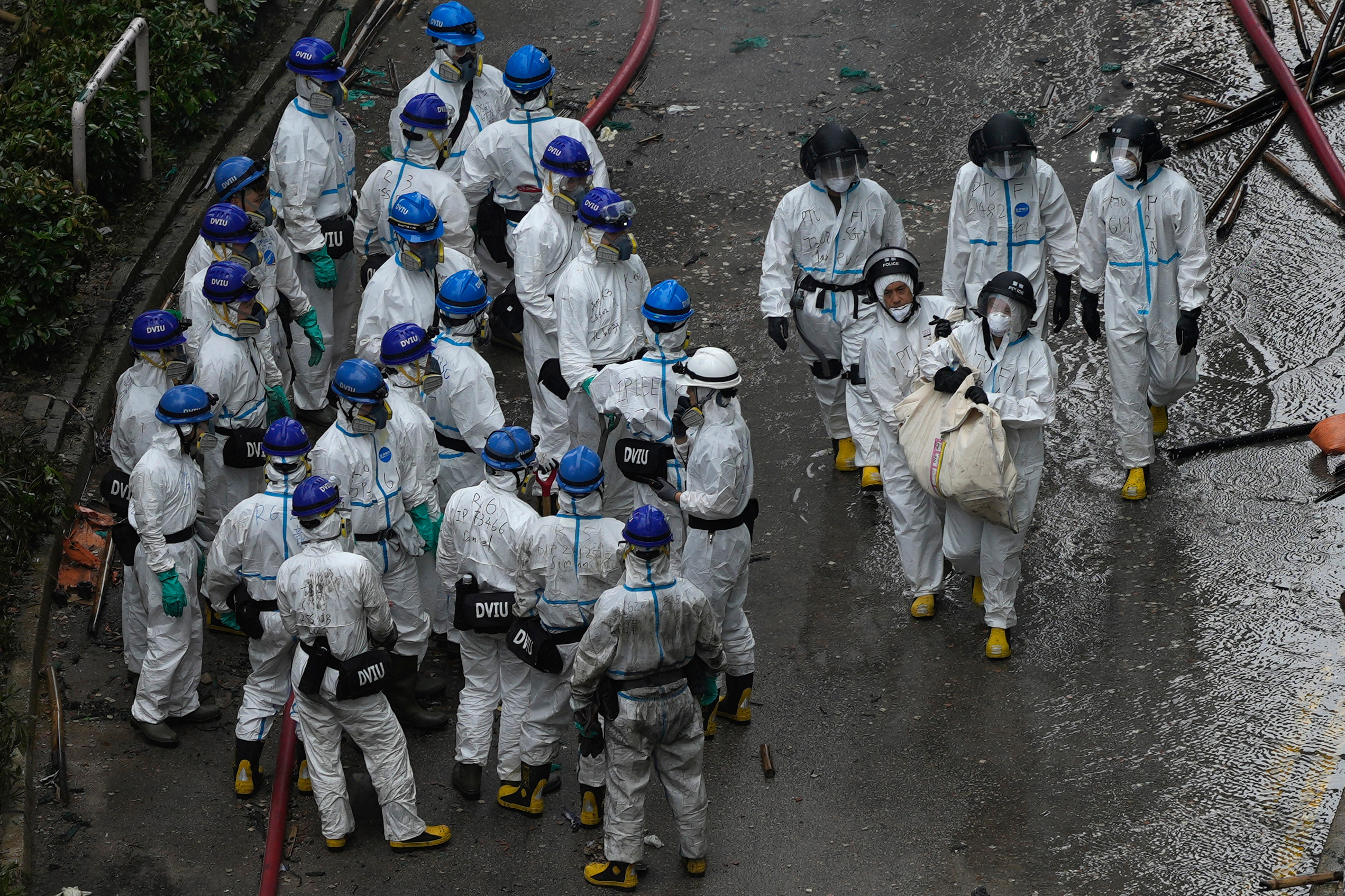 Emergency crew remove what appears to be a body bag from the site of a fire.