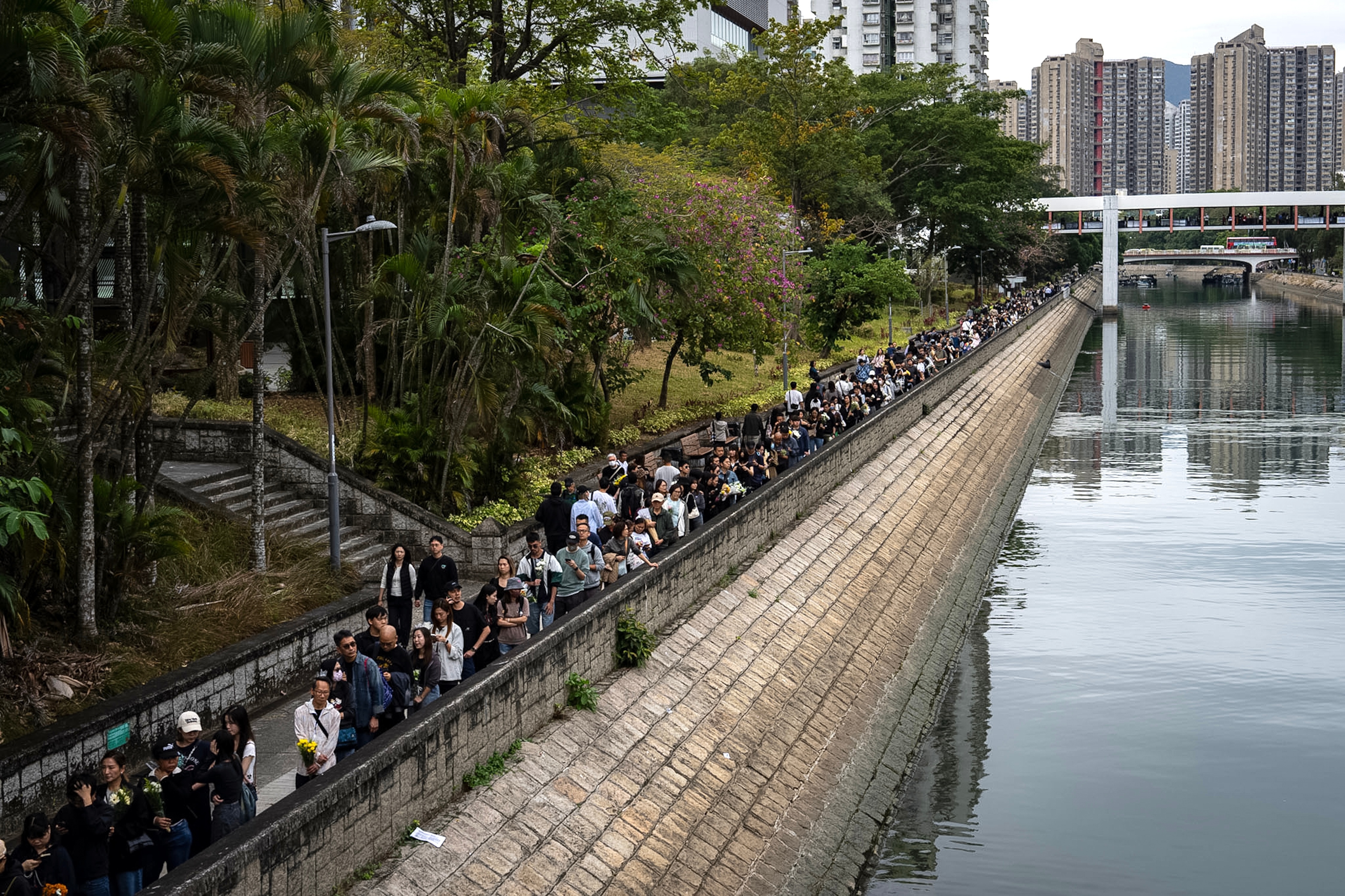 People line up to offer flowers and prayers for the victims near the site of a deadly Wednesday fire at Wang Fuk Court, a residential estate in the Tai Po district of Hong Kong's New Territories on Sunday, Nov. 30, 2025. (AP Photo/Chan Long Hei)