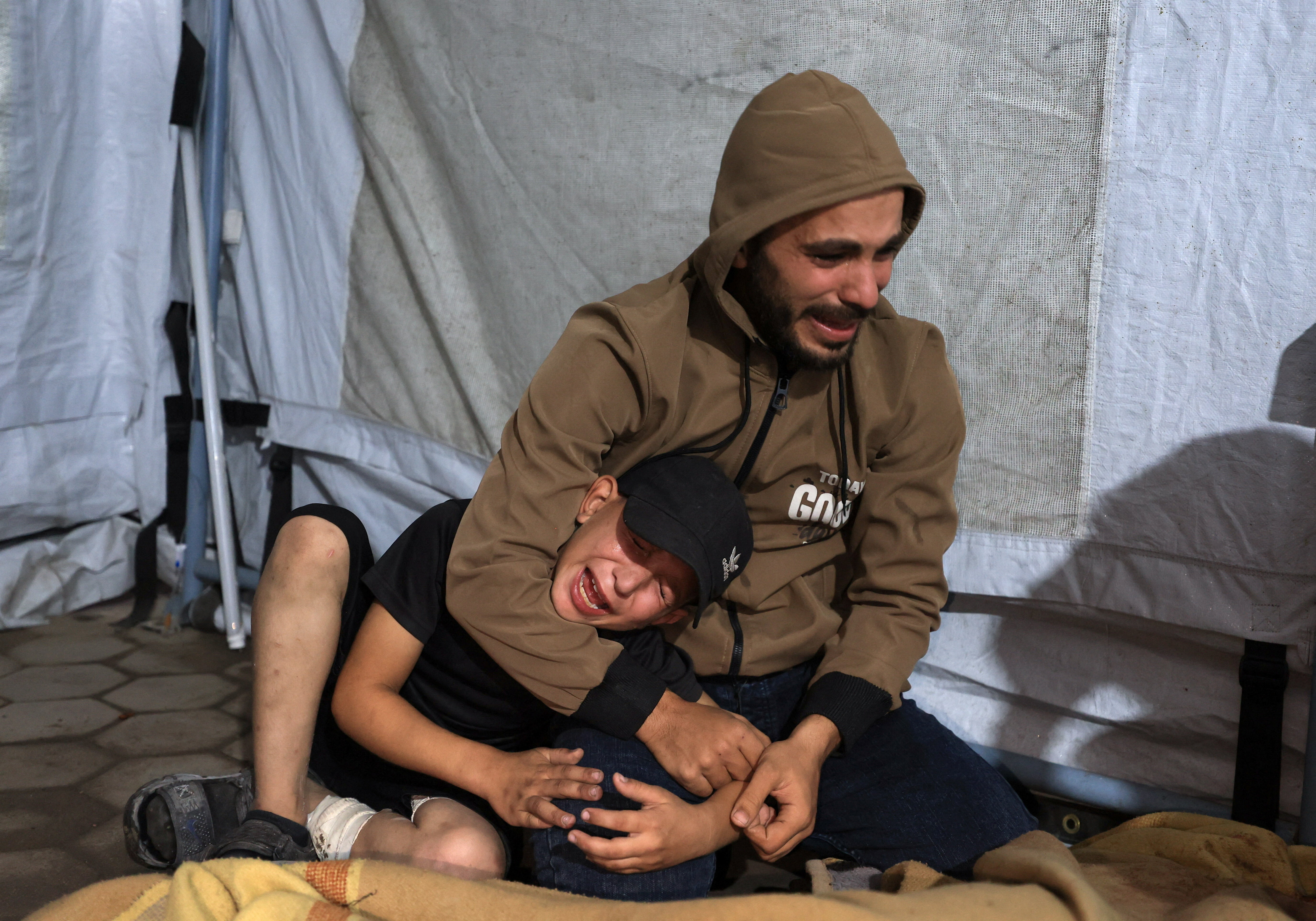 A man and a child mourn by the covered body of a Palestinian killed in an Israeli air strike, according to medics, at Al-Ahli Arab Hospital in Gaza City November 19, 2025. REUTERS/Dawoud Abu Alkas