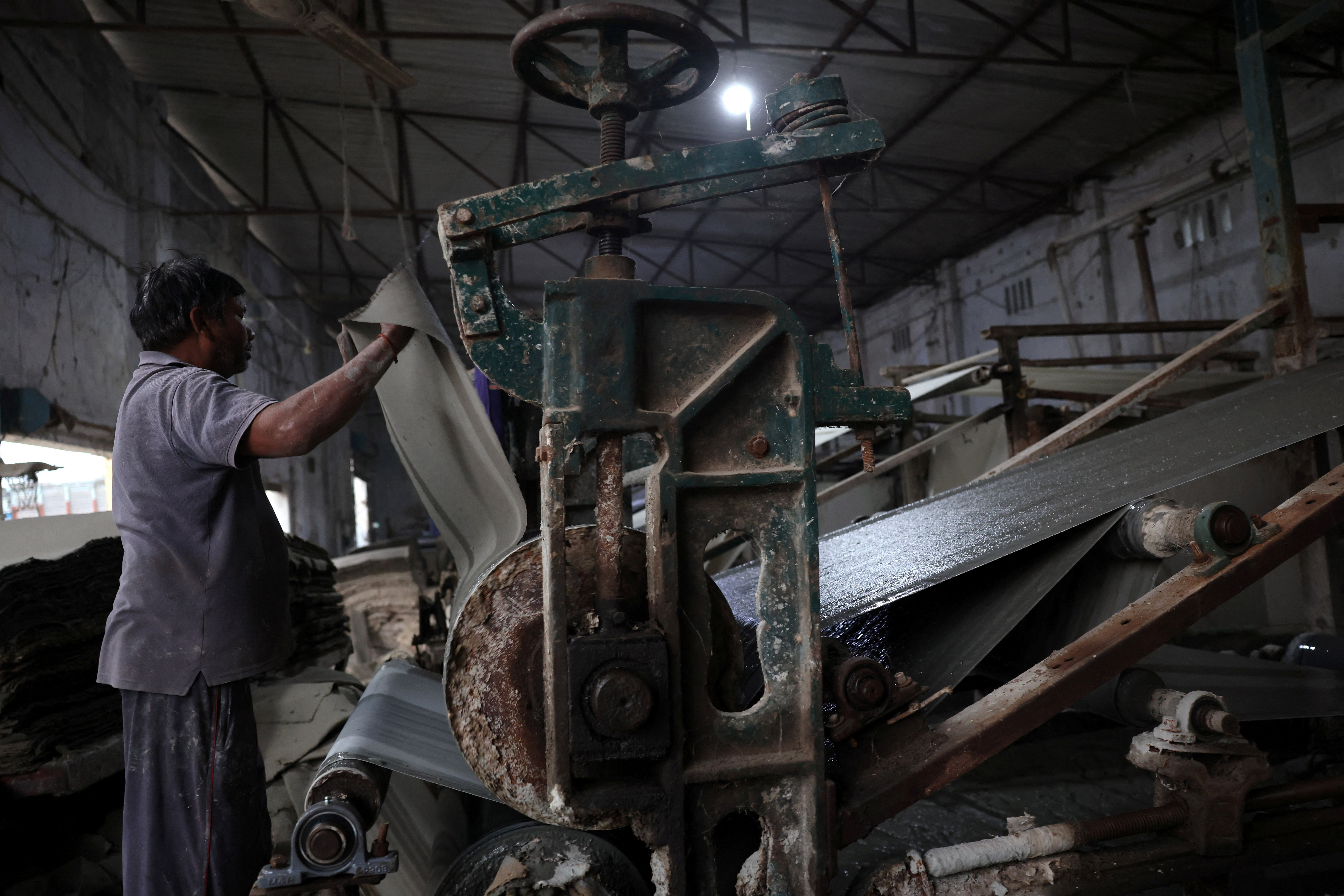 A factory worker holds a cardboard sheet made of leftover paddy stubble and paper pulp as an alternative to stubble burning, amid the ongoing air pollution, at Phaguwala village in the northern state of Punjab, India, November 13, 2025. REUTERS/Bhawika Chhabra