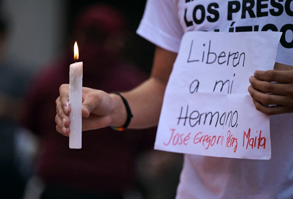 A man holds a candle and a sign asking for the release of his brother, during a vigil called by the opposition demanding freedom for political prisoners arrested during protest following the contested re-election of Venezuelan President Nicolas Maduro in Caracas. [File: Yuri Cortez/AFP]