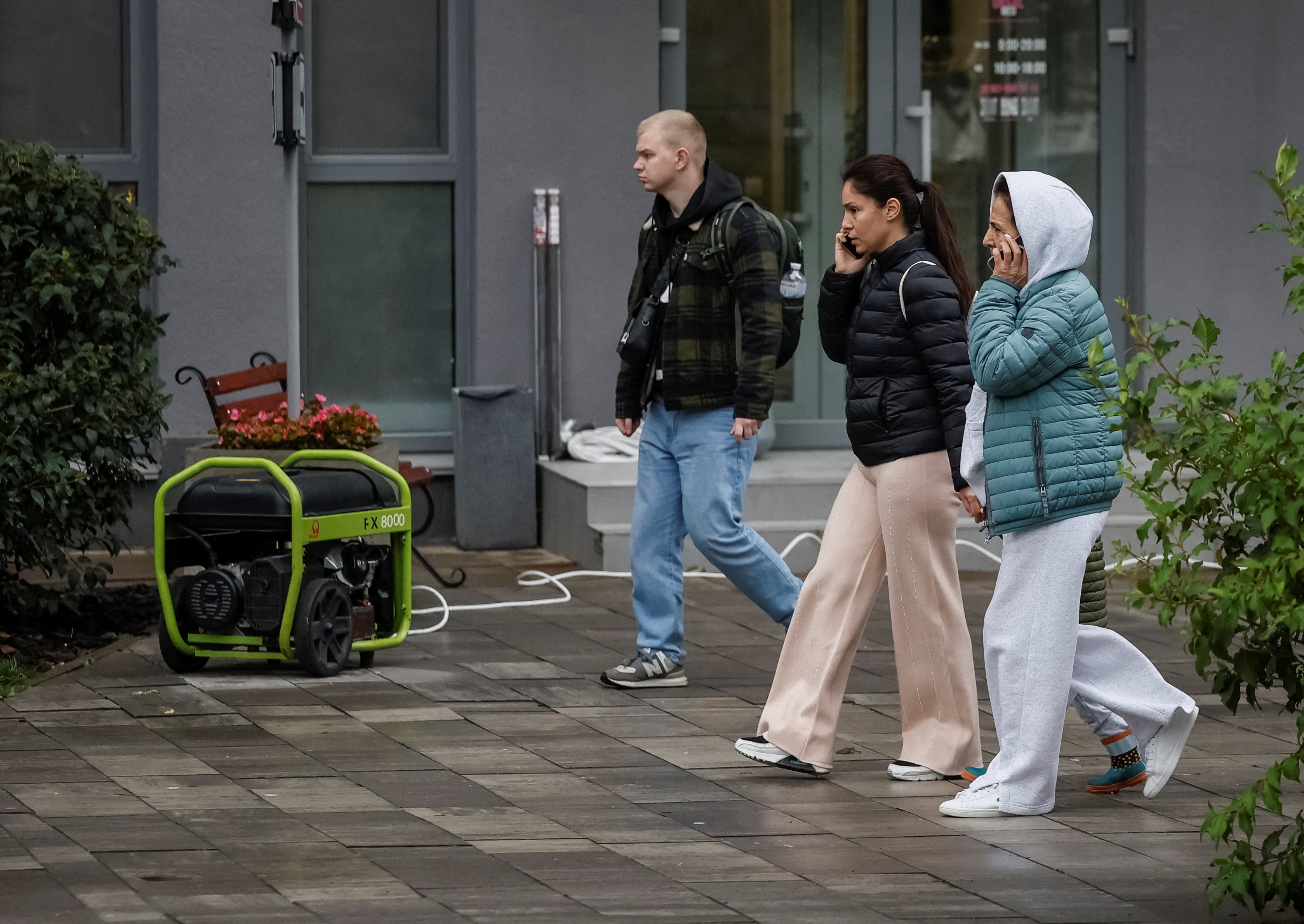 People walk near a petrol-run generator used to generate electricity for medical clinic during a power blackout after critical civil infrastructure was hit by a Russian missile and drone attacks, amid Russia's attack on Ukraine, in Kyiv, Ukraine October 10, 2025. REUTERS/Gleb Garanich