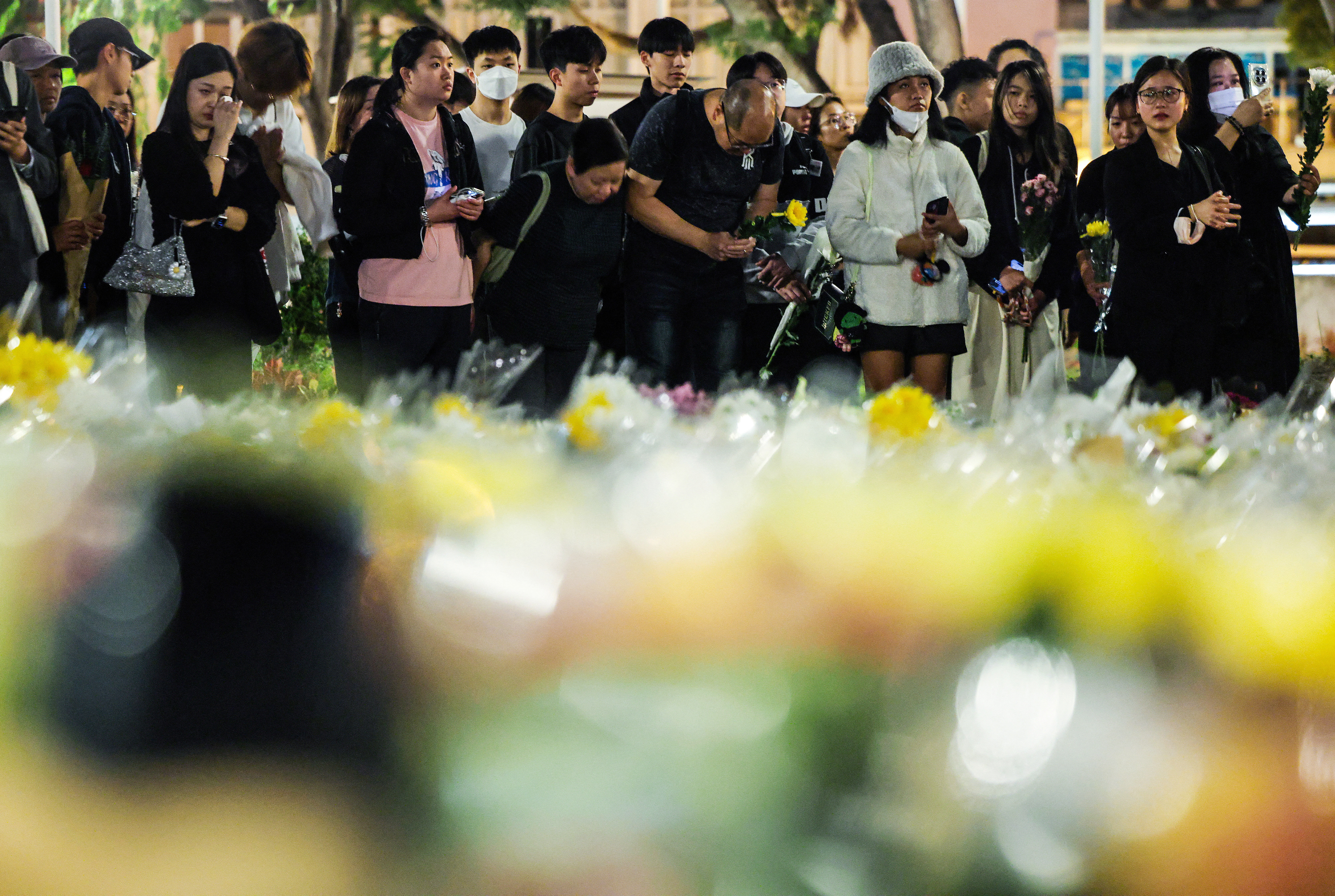 People pray as they lay flowers at a makeshift memorial near the Wang Fuk Court housing complex residents after the deadly fire, in Tai Po, Hong Kong, China, December 1, 2025. REUTERS/Maxim Shemetov