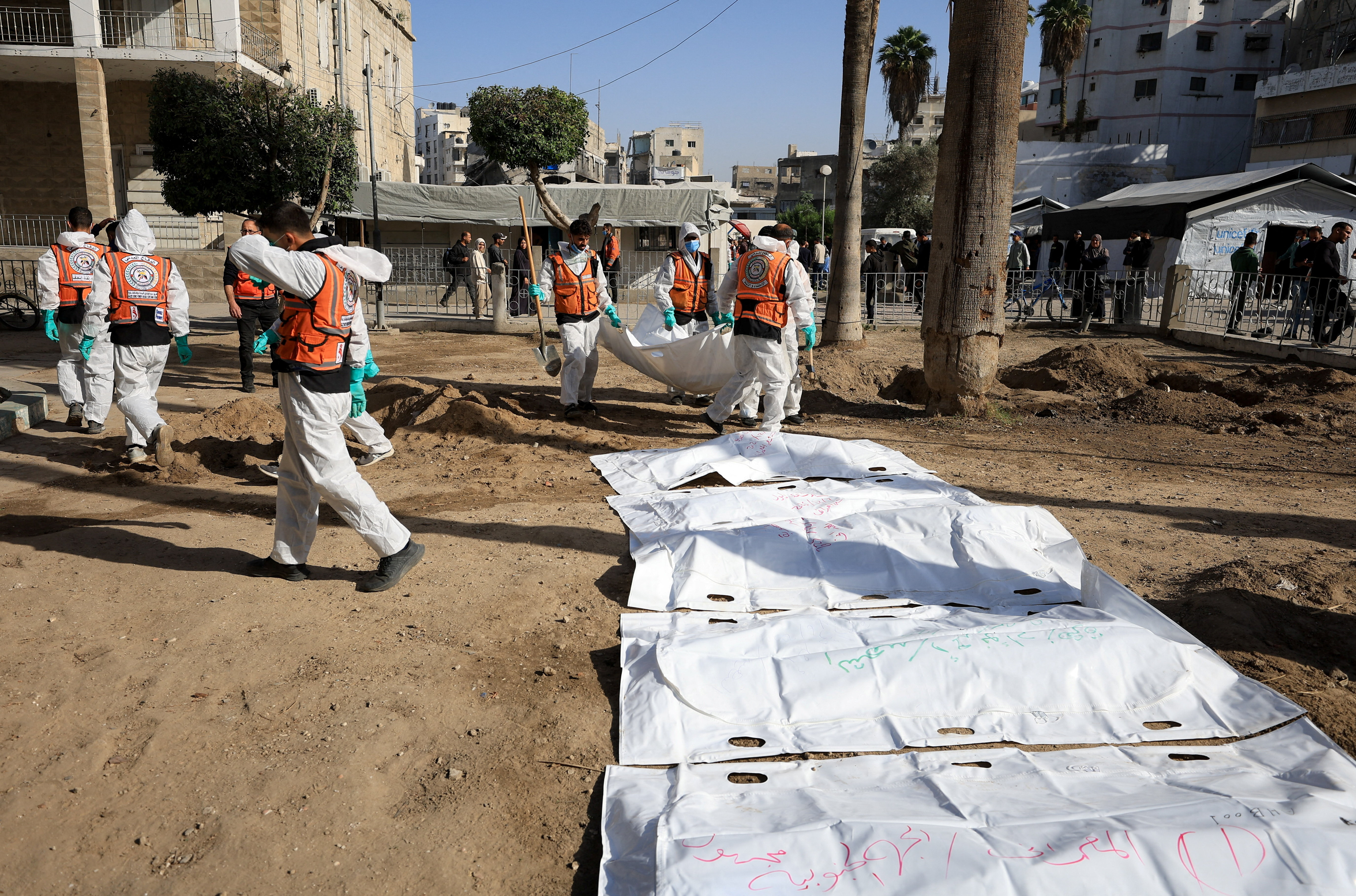 Members of the Palestinian Civil Defence work to exhume bodies of people killed in Israeli raids for reburial at al-Ahli Arab Hospital in Gaza City