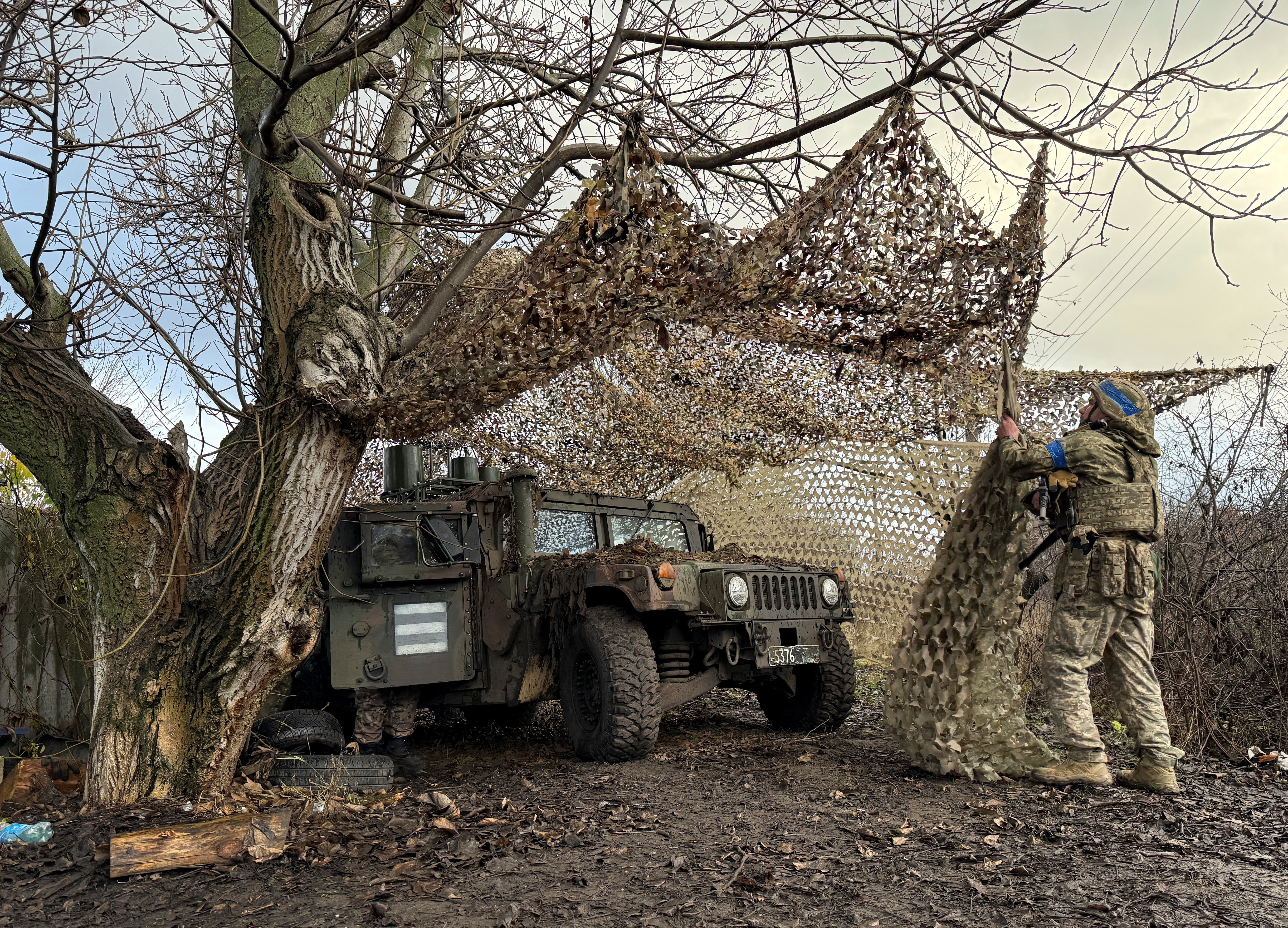 A Ukrainian serviceman camouflages a vehicle.