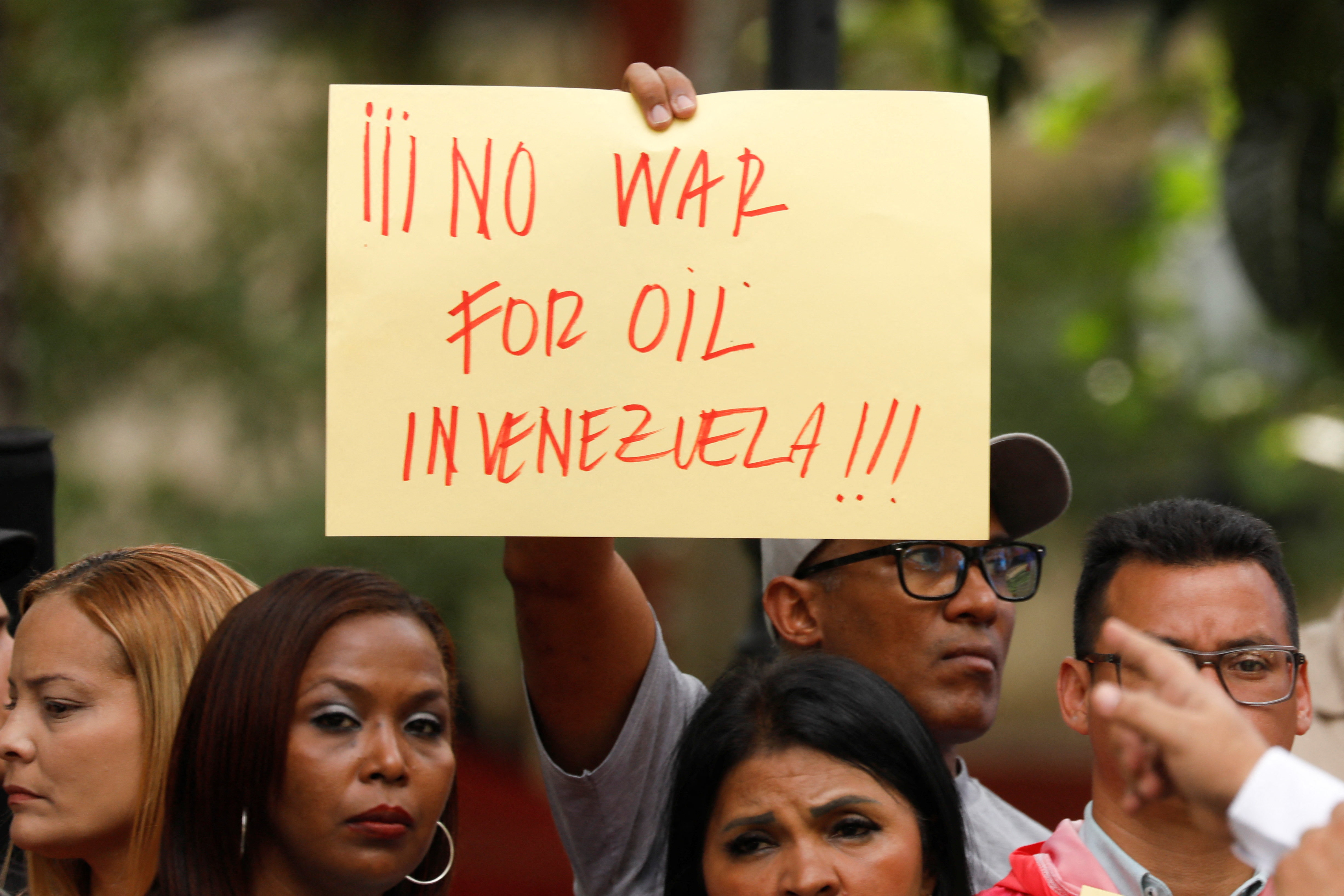 A protester in Venezuela holds a sign that reads, "No war for oil in Venezuela."