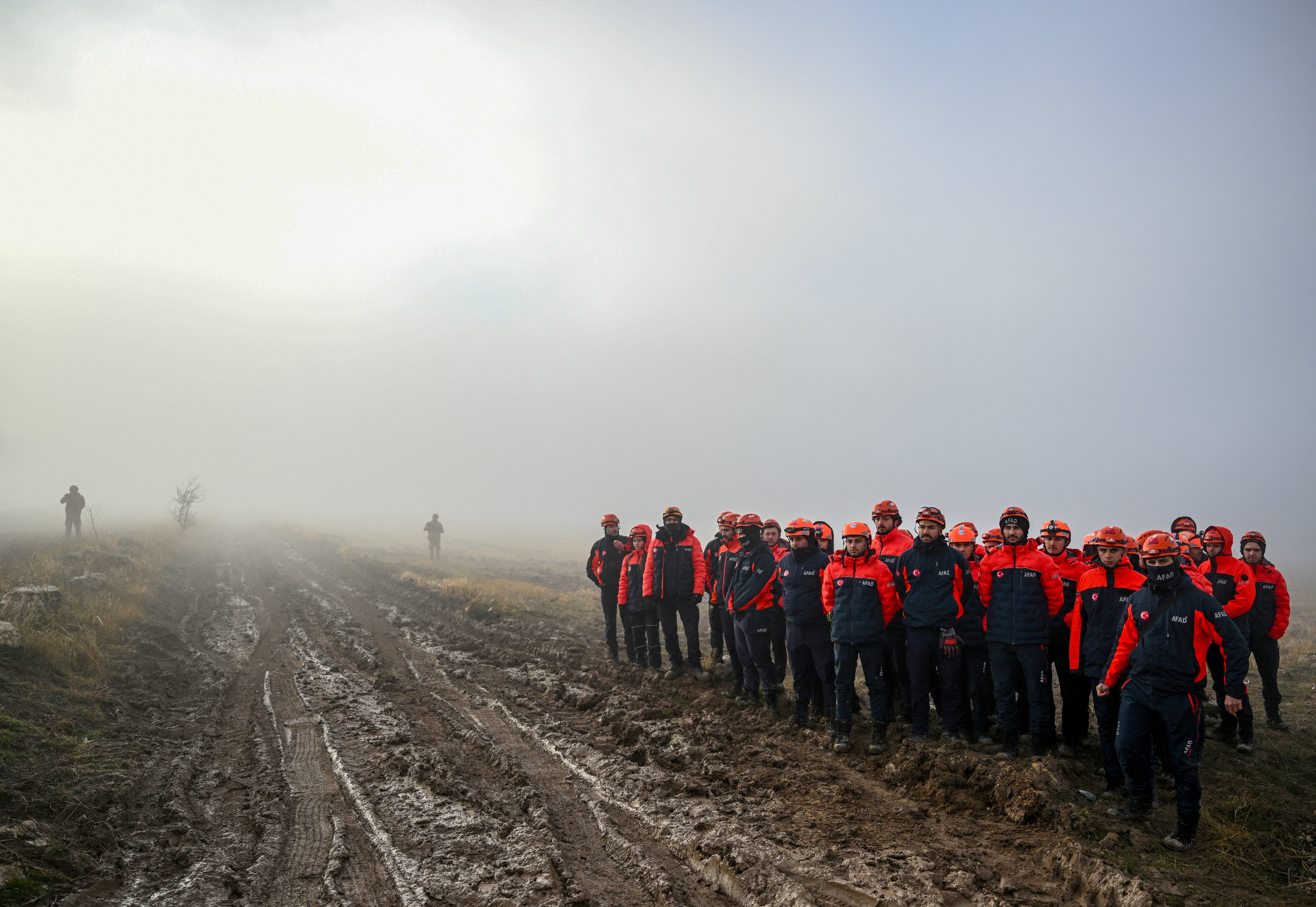 Rescuers standing next to a muddy road