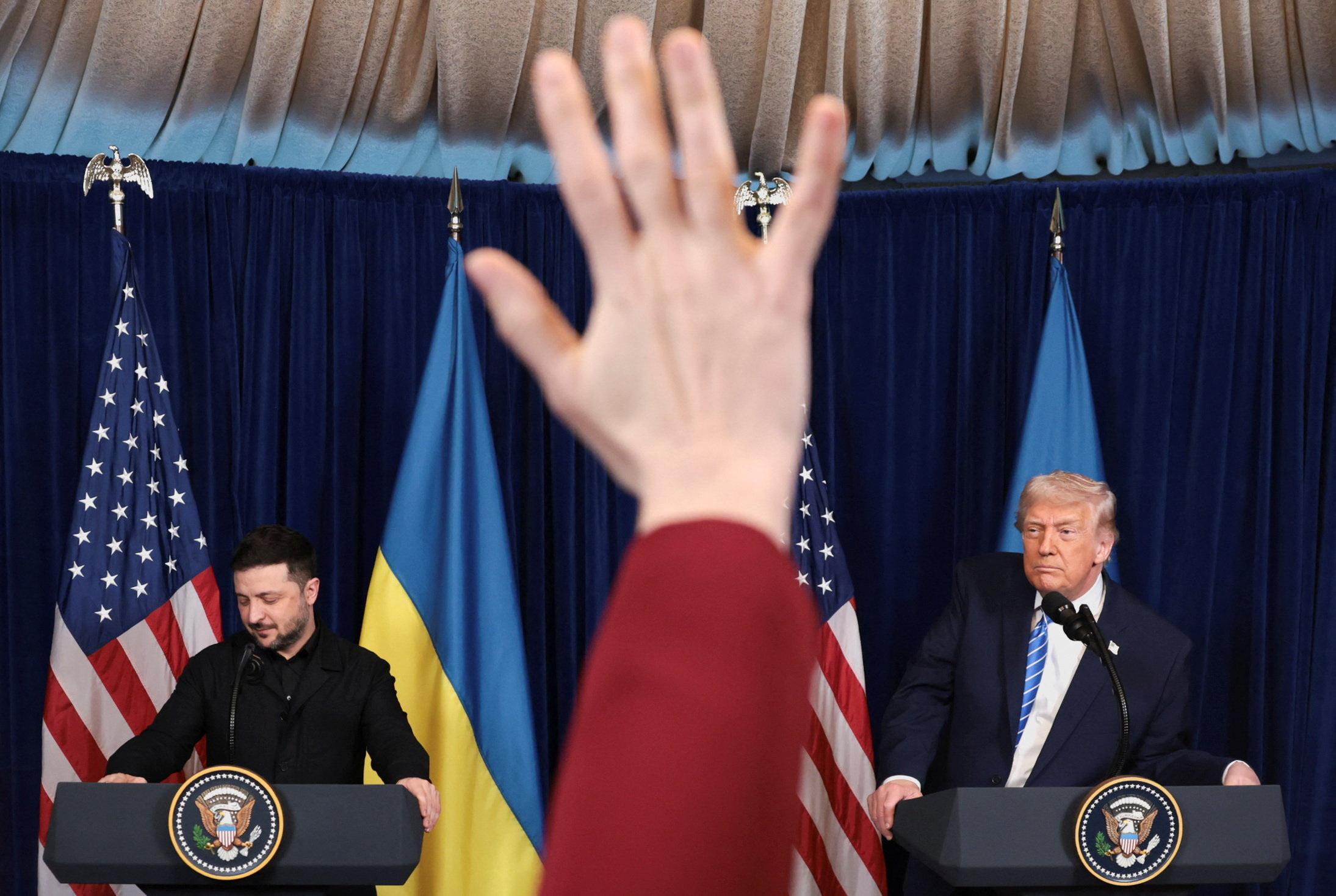 A reporter raises a hand at a news conference for Volodymyr Zelenskyy and Donald Trump