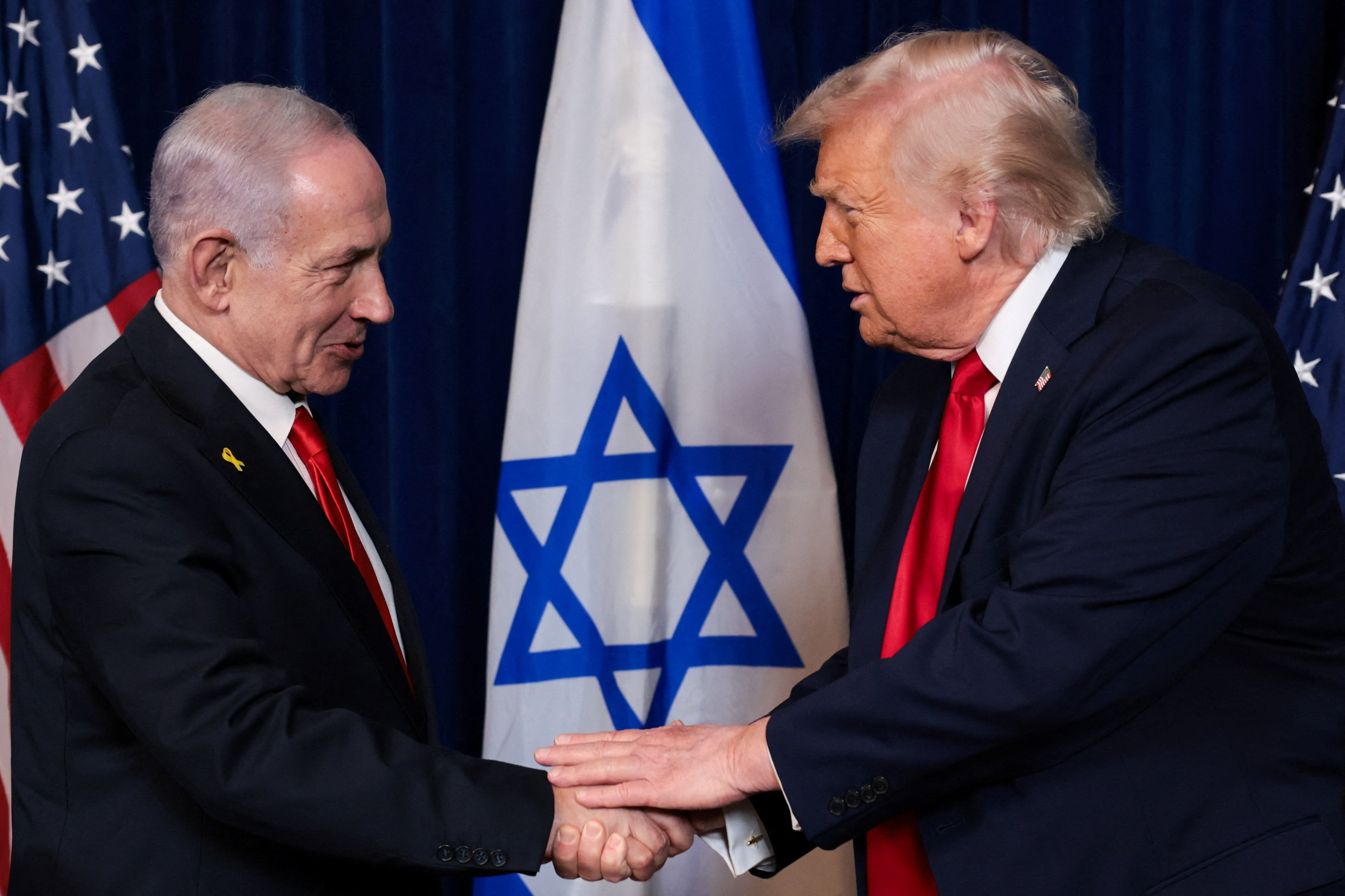 Netanyahu and Trump shake hands in front of Israel flag