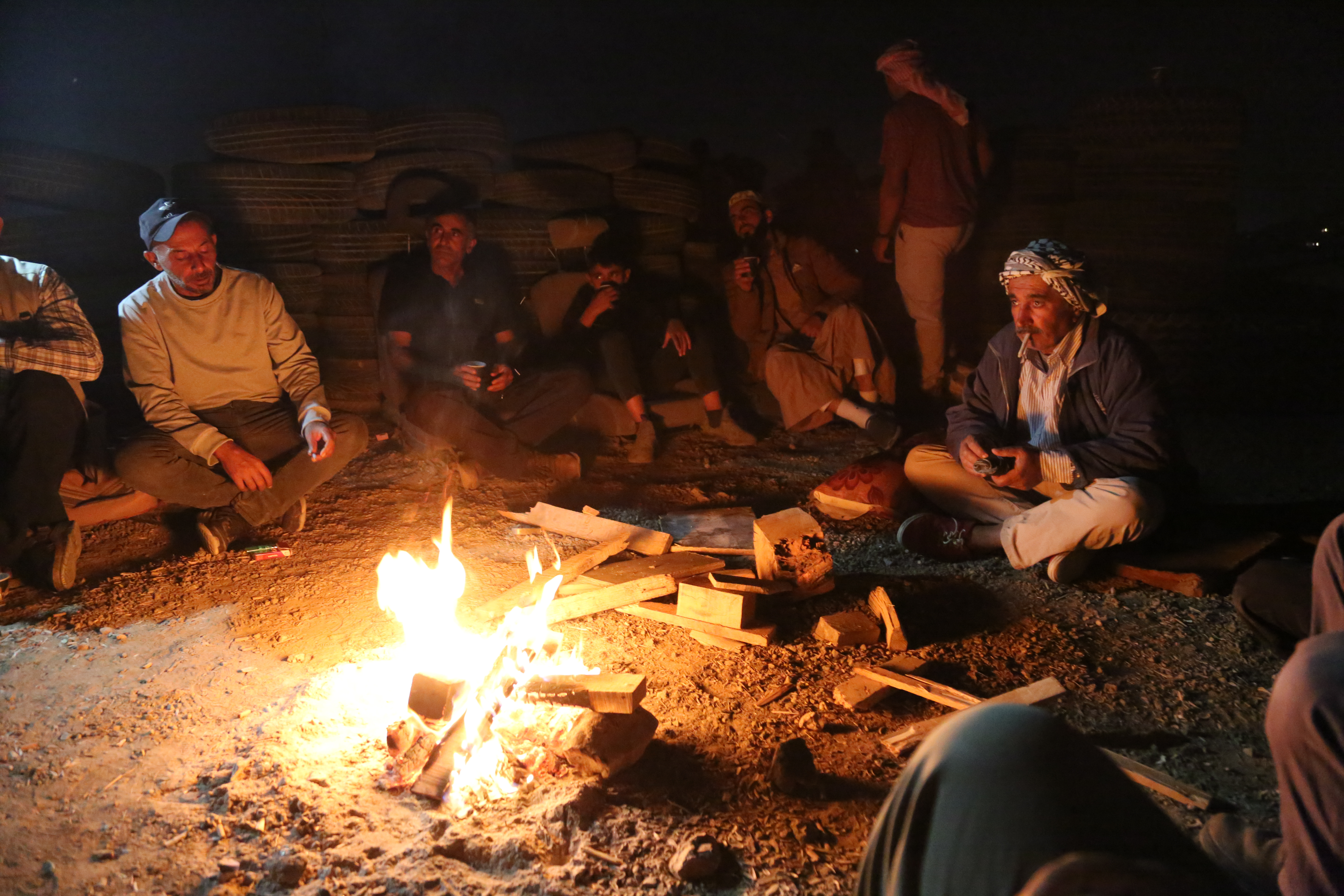 a circle of men around a fire