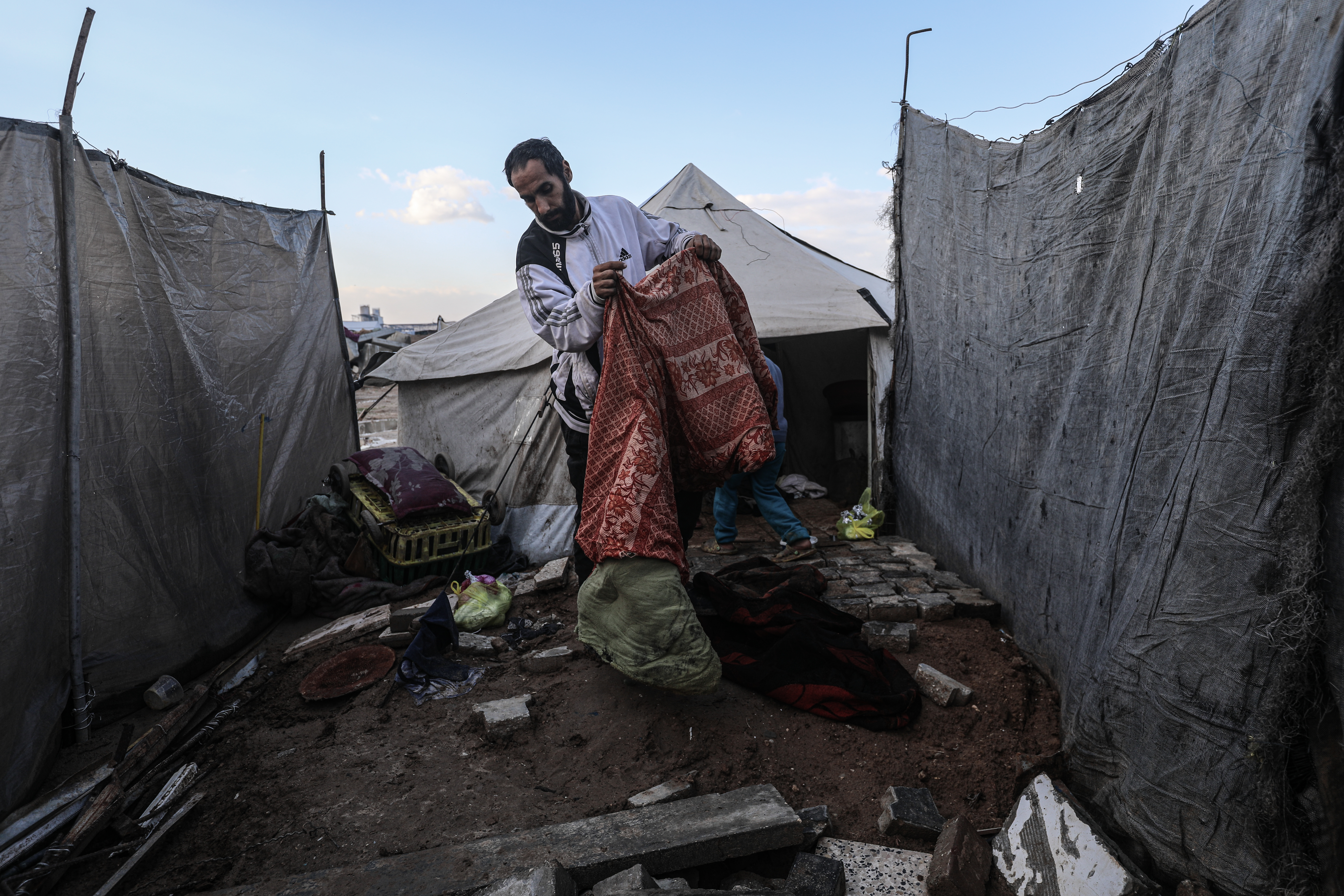 A man lifts his possessions from a flooded tent.
