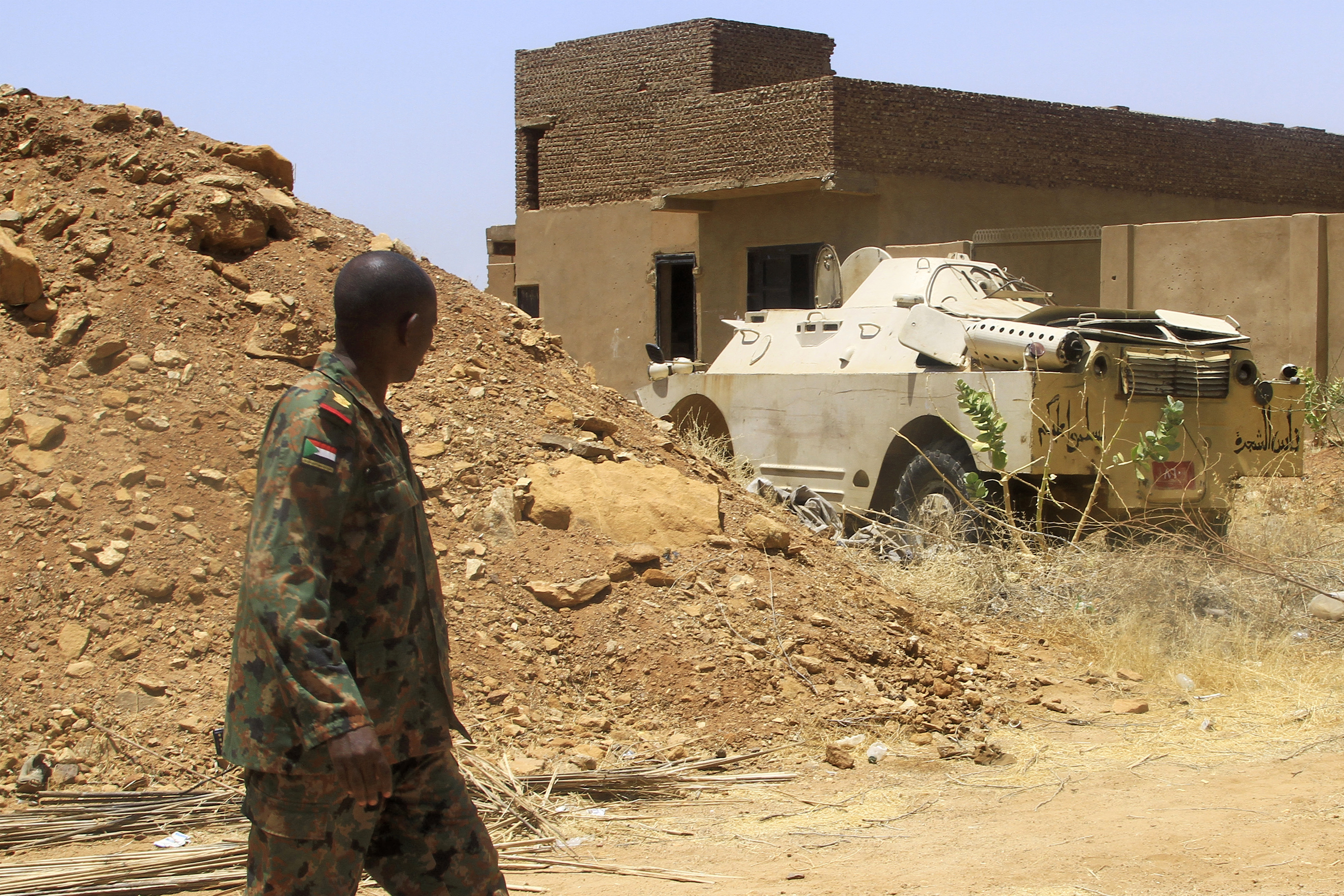 A Sudanese army officer walks near an armoured vehicle.