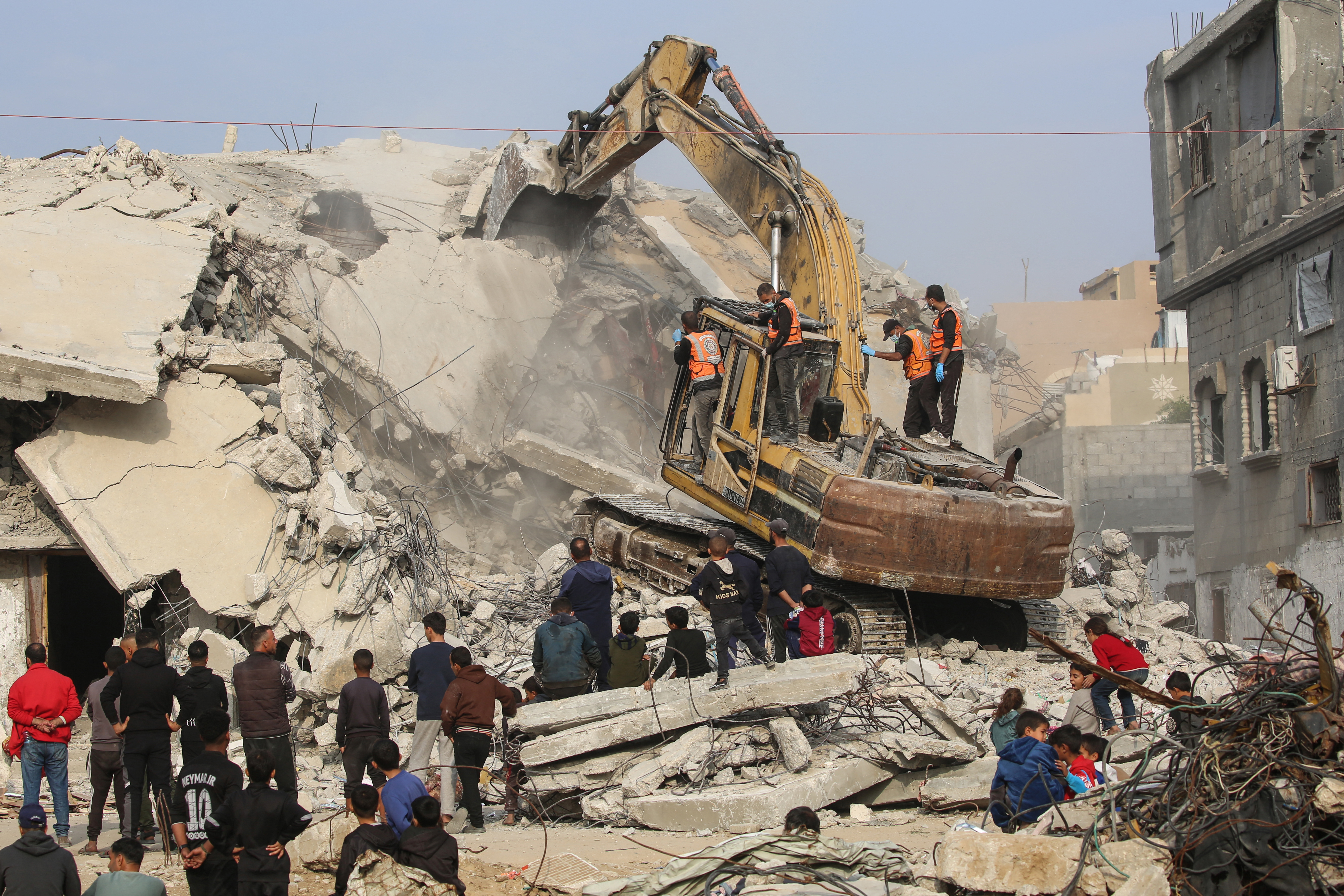 Gaza Civil Defence personnel use an excavator to search for the remains of victims
