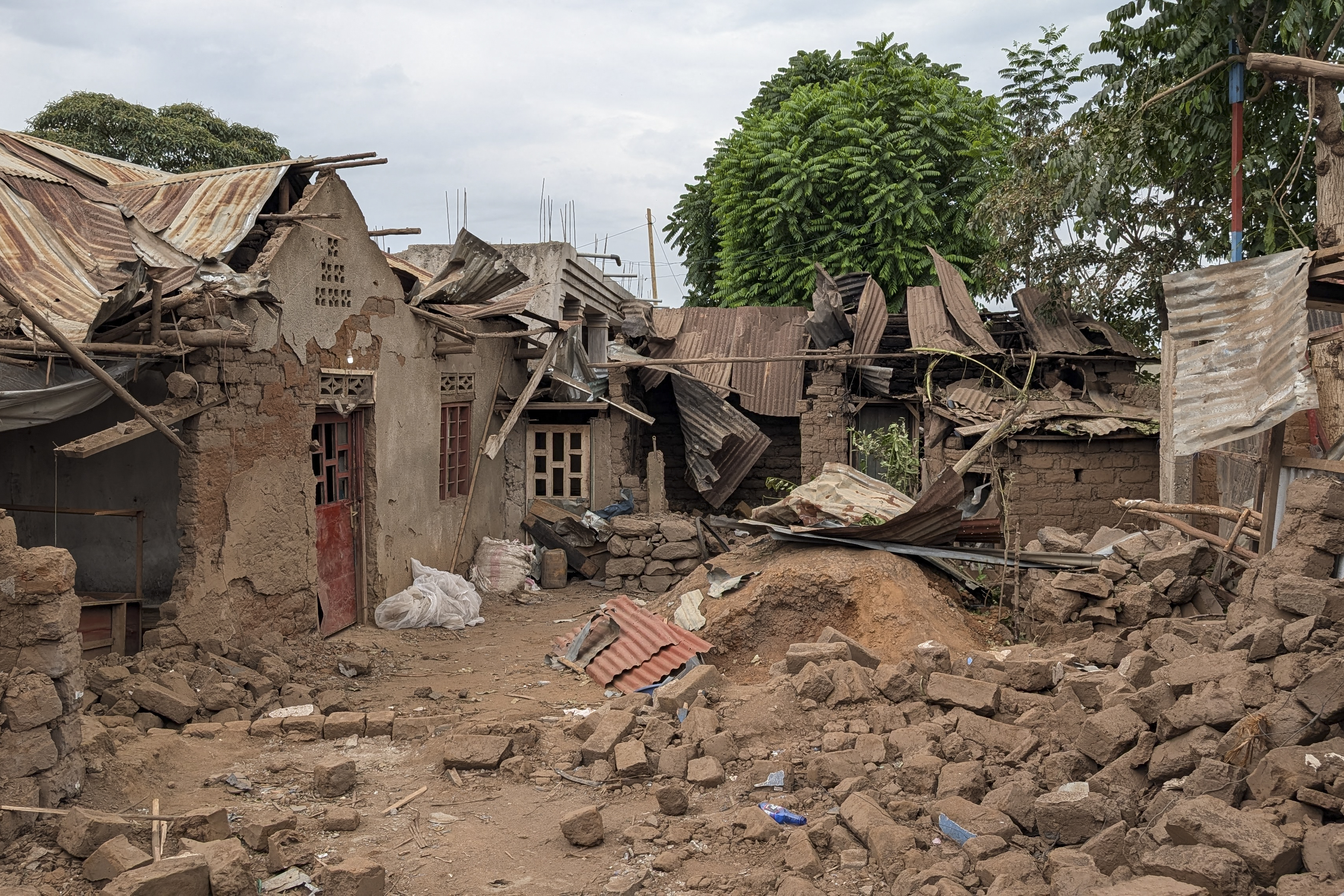 Houses destroyed by shelling behind a pile of rubble.
