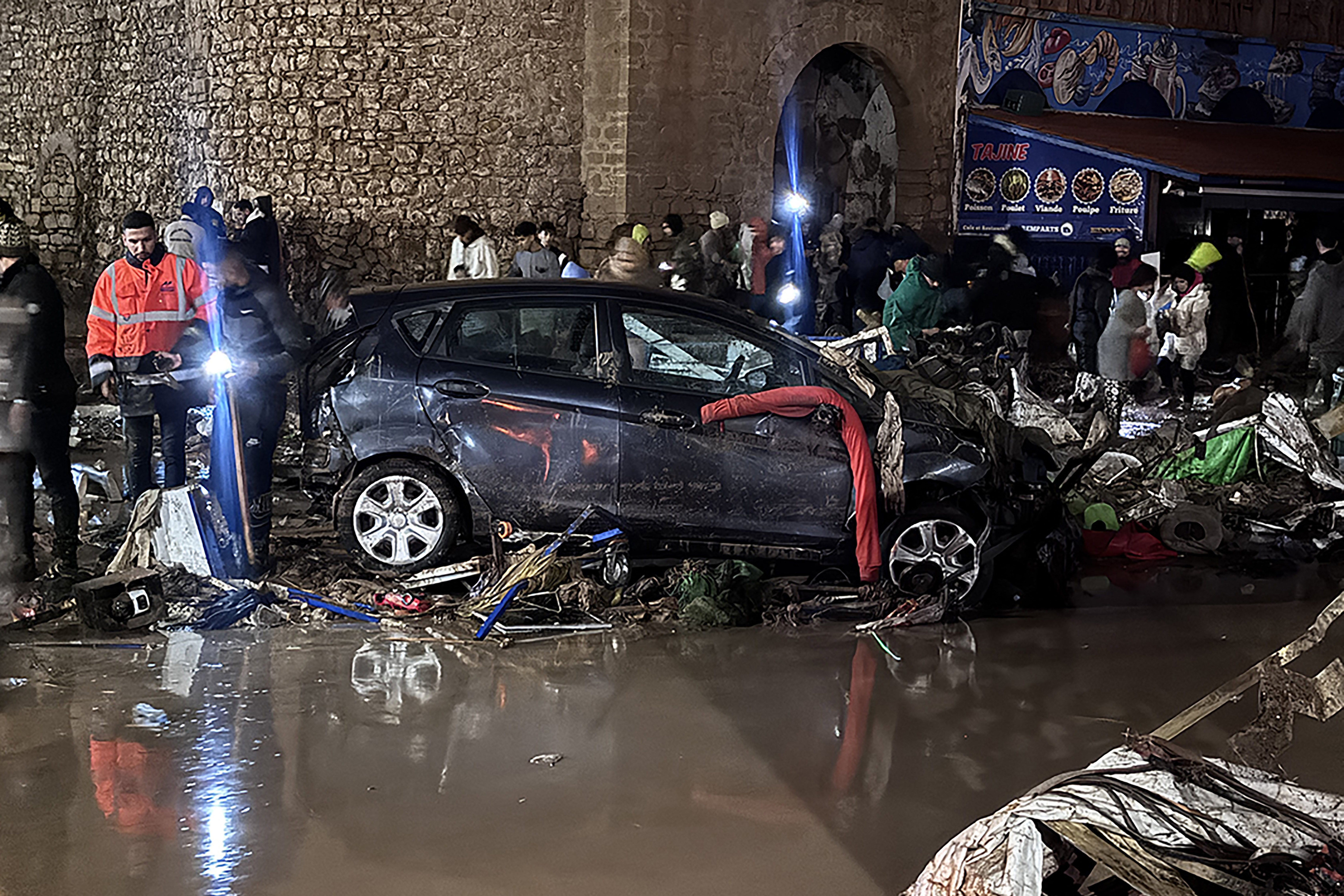 People walk past debris left by a flash flood in Safi