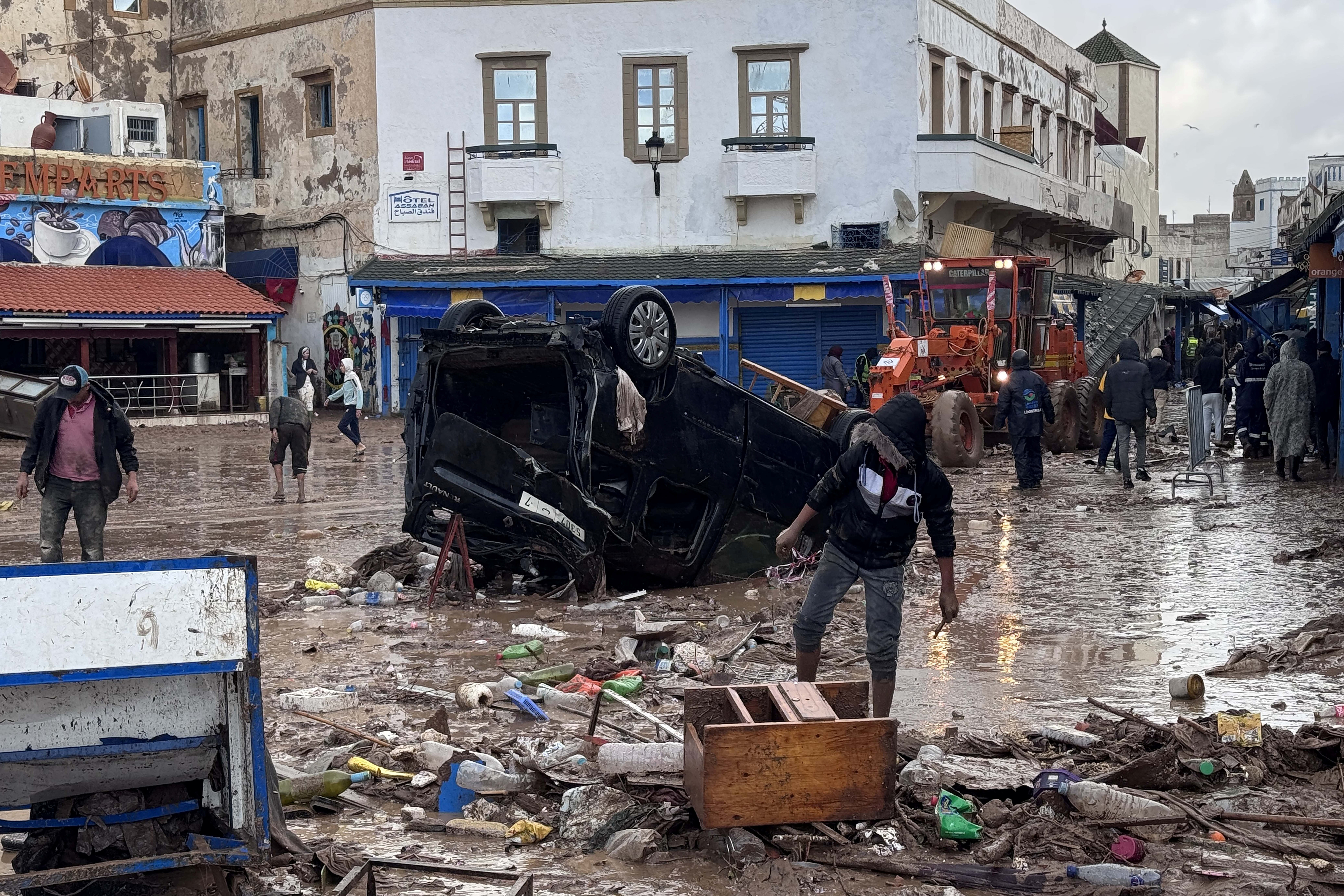Moroccans looks at a destroyed vehicle and other debris following a flash flood.