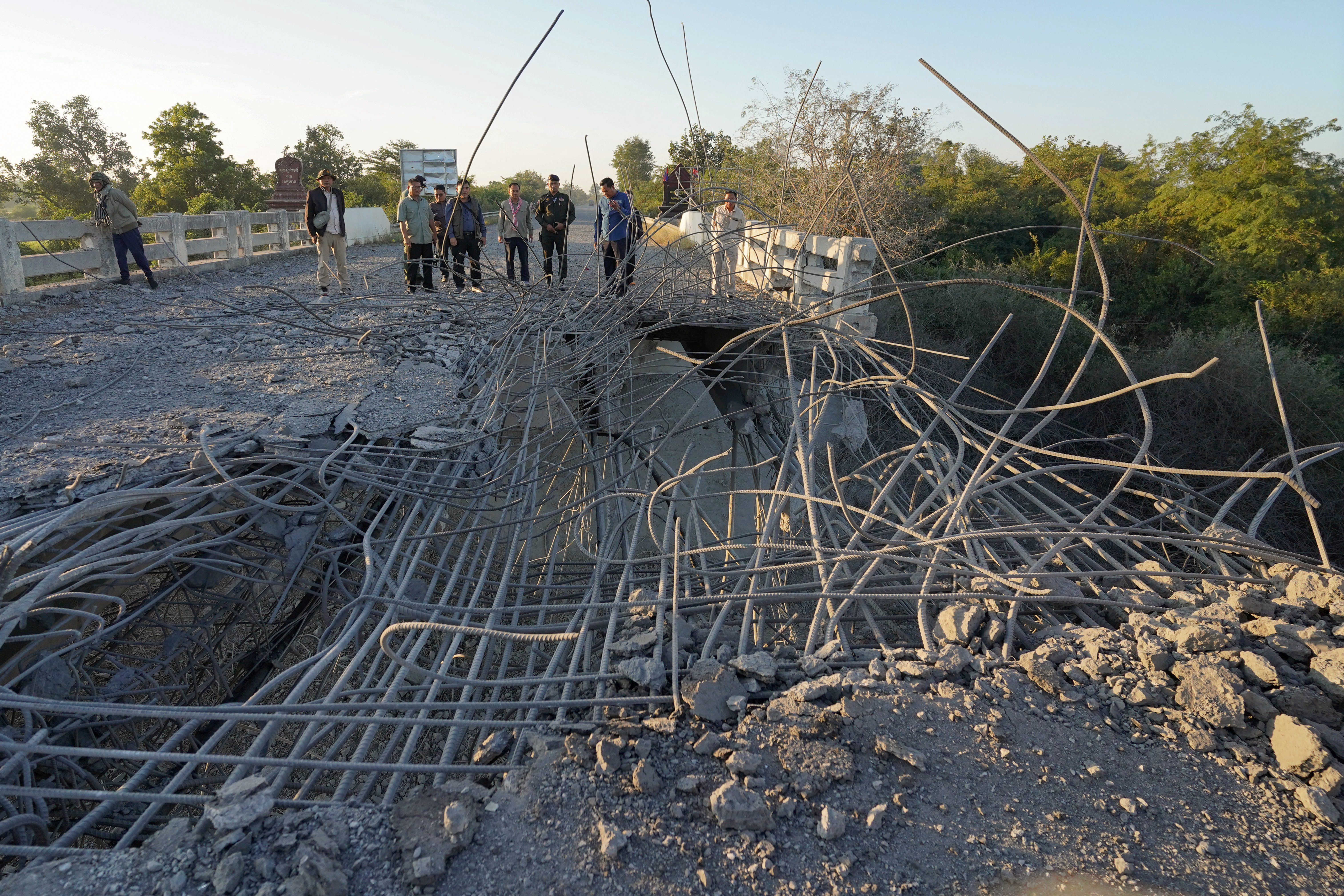 People look at a damaged bridge after Thailand carried out air strikes in an area between Cambodia's Oddar Meanchey and Siem Reap provinces on December 20, 2025.