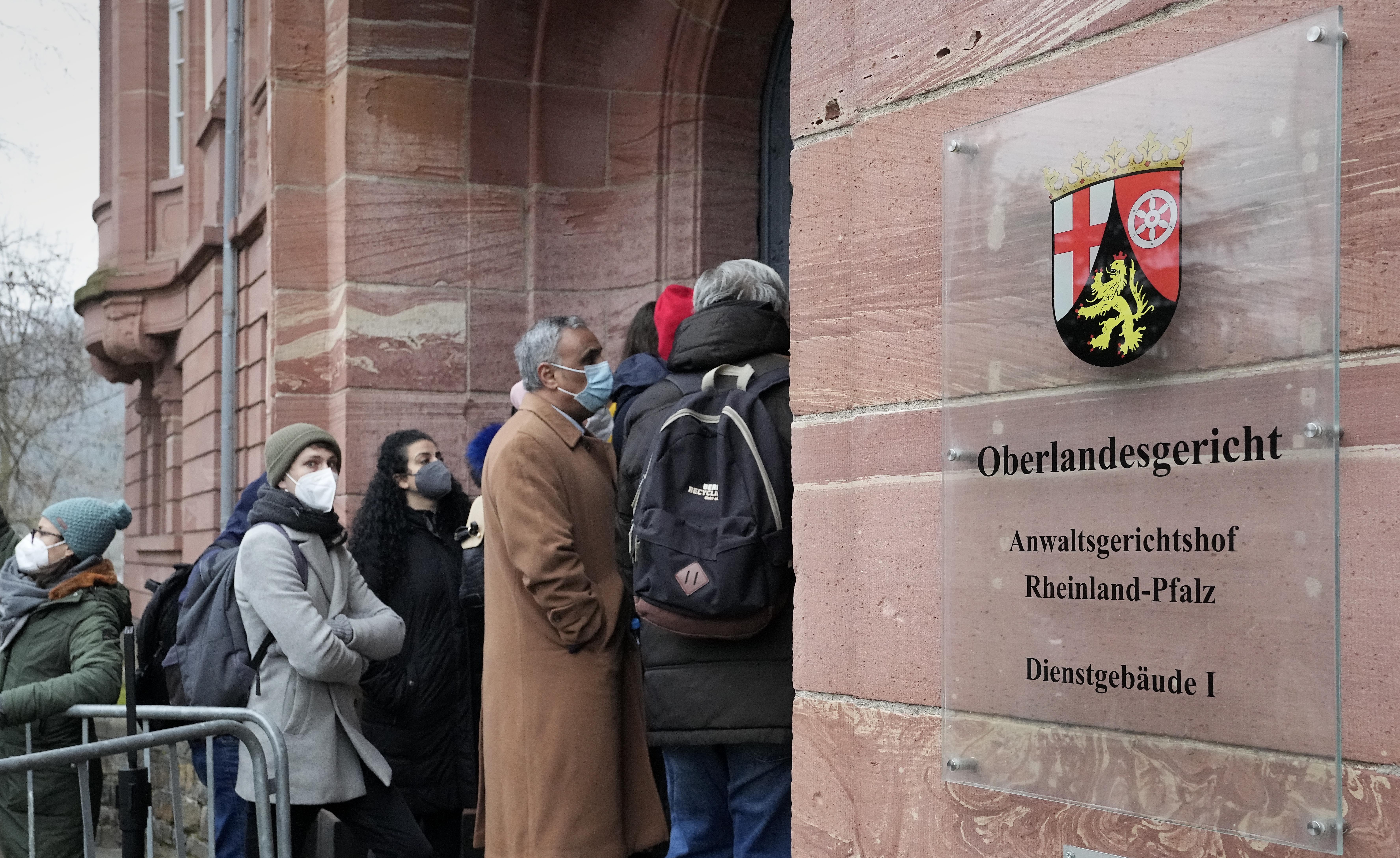 People line up in front of the court in Koblenz, Germany, Thursday, Jan. 13, 2022. The German court has convicted a former Syrian secret police officer of crimes against humanity for overseeing the abuse of detainees at a jail near Damascus a decade ago. (AP Photo/Martin Meissner)