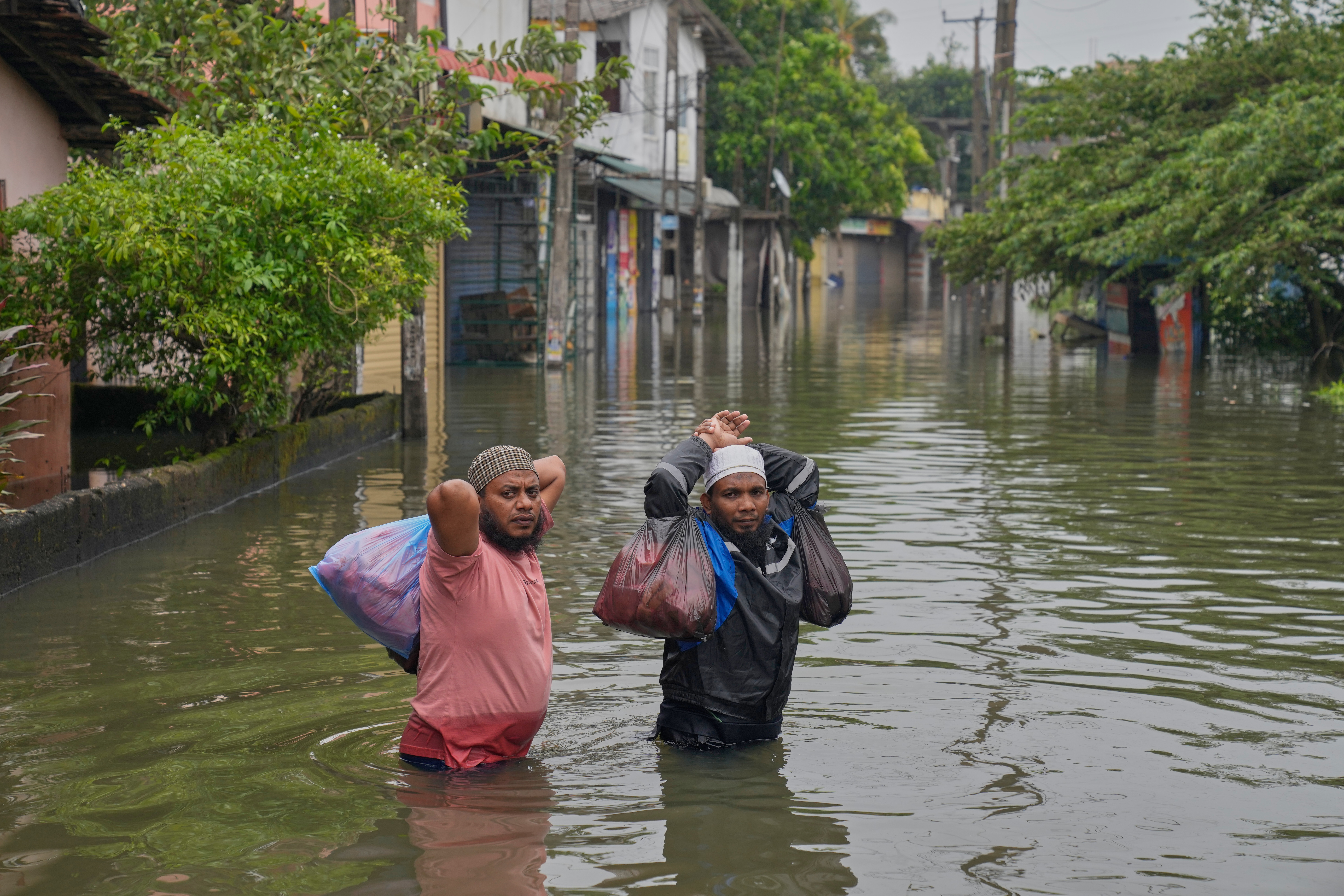 FILE - People wade through floodwaters in Colombo, Sri Lanka, Nov. 29, 2025. (AP Photo/Eranga Jayawardena, File)