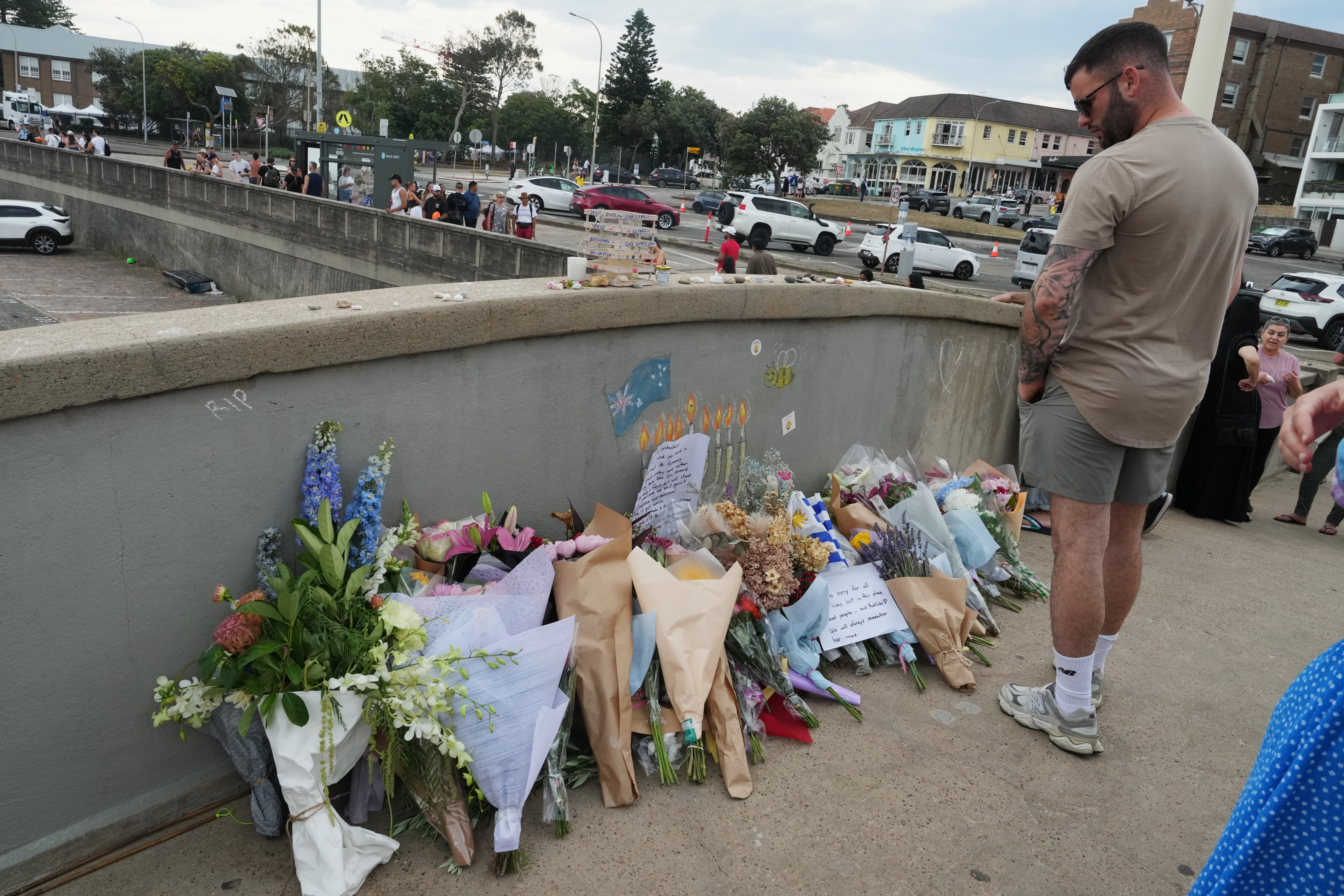 A man looks at a flower tribute on the bridge at Bondi Beach in Sydney, Australia