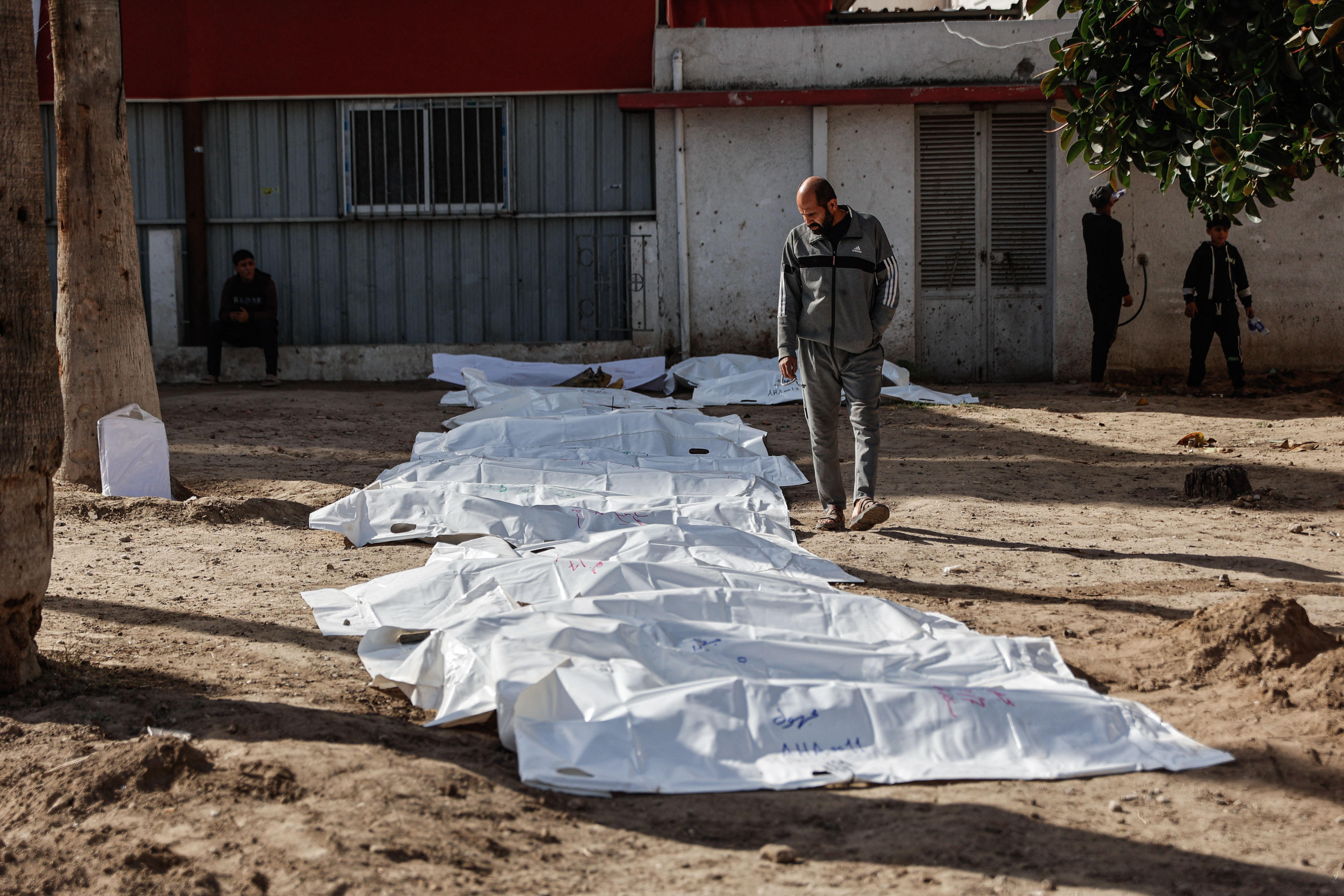 A man looks at body bags containing human remains.