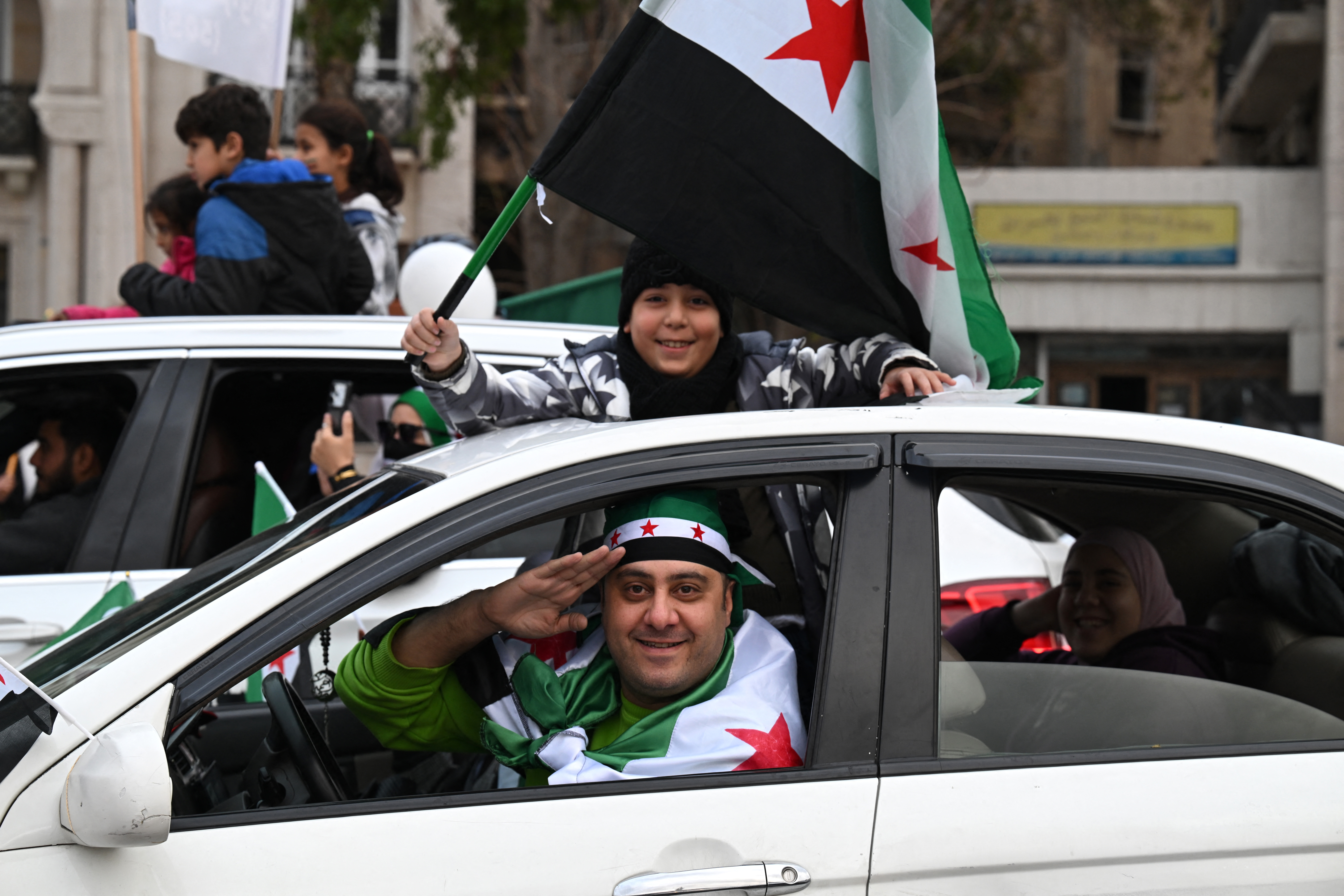 A boy waves a Syrian flag as they celebrate a year since the ousting of longtime ruler Bashar al-Assad in the Syrian capital Damascus on December 8, 2025.