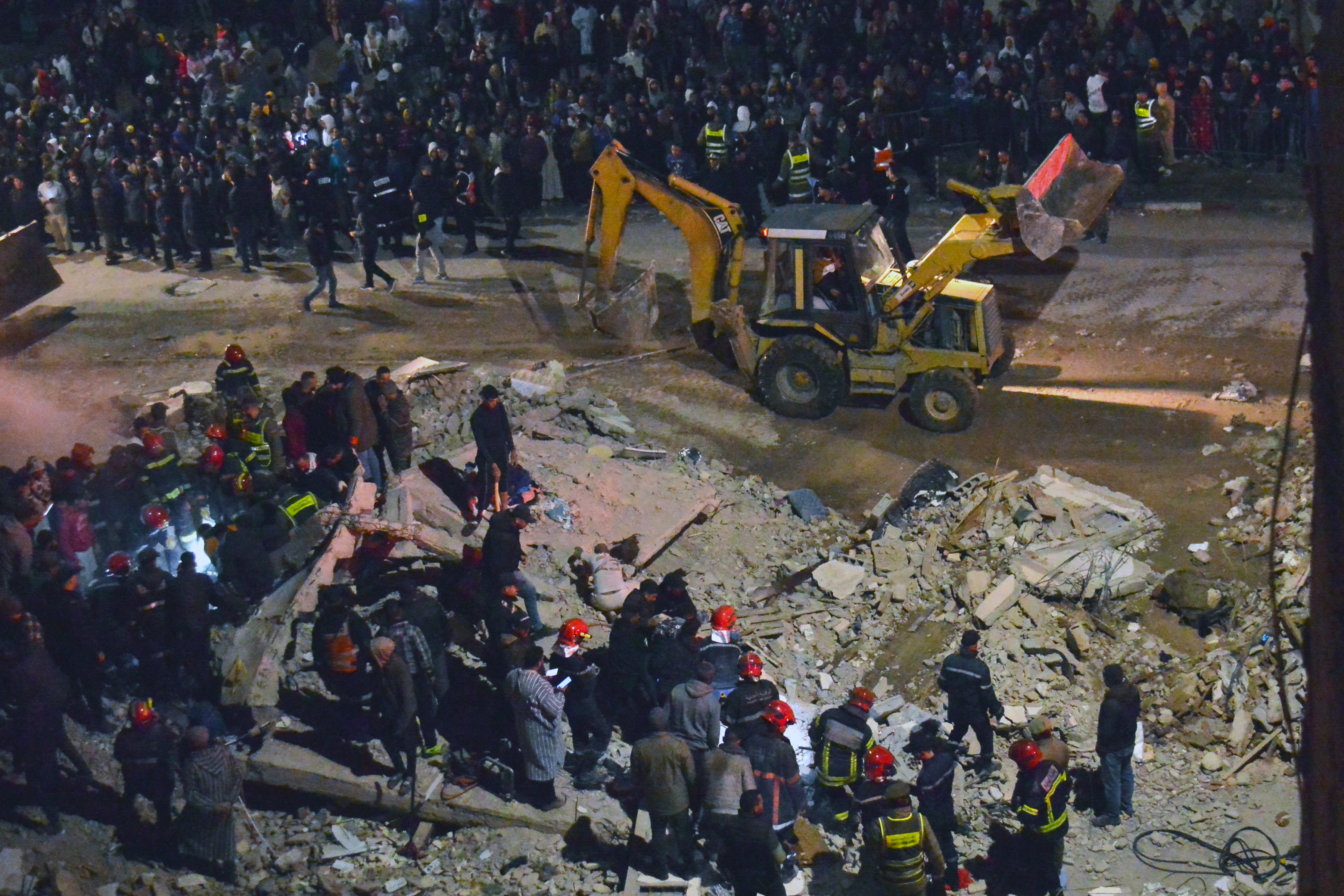 Emergency personnel search for victims in the rubble of two collapsed buildings in the Al Massira area of Fes late on December 9, 2025.