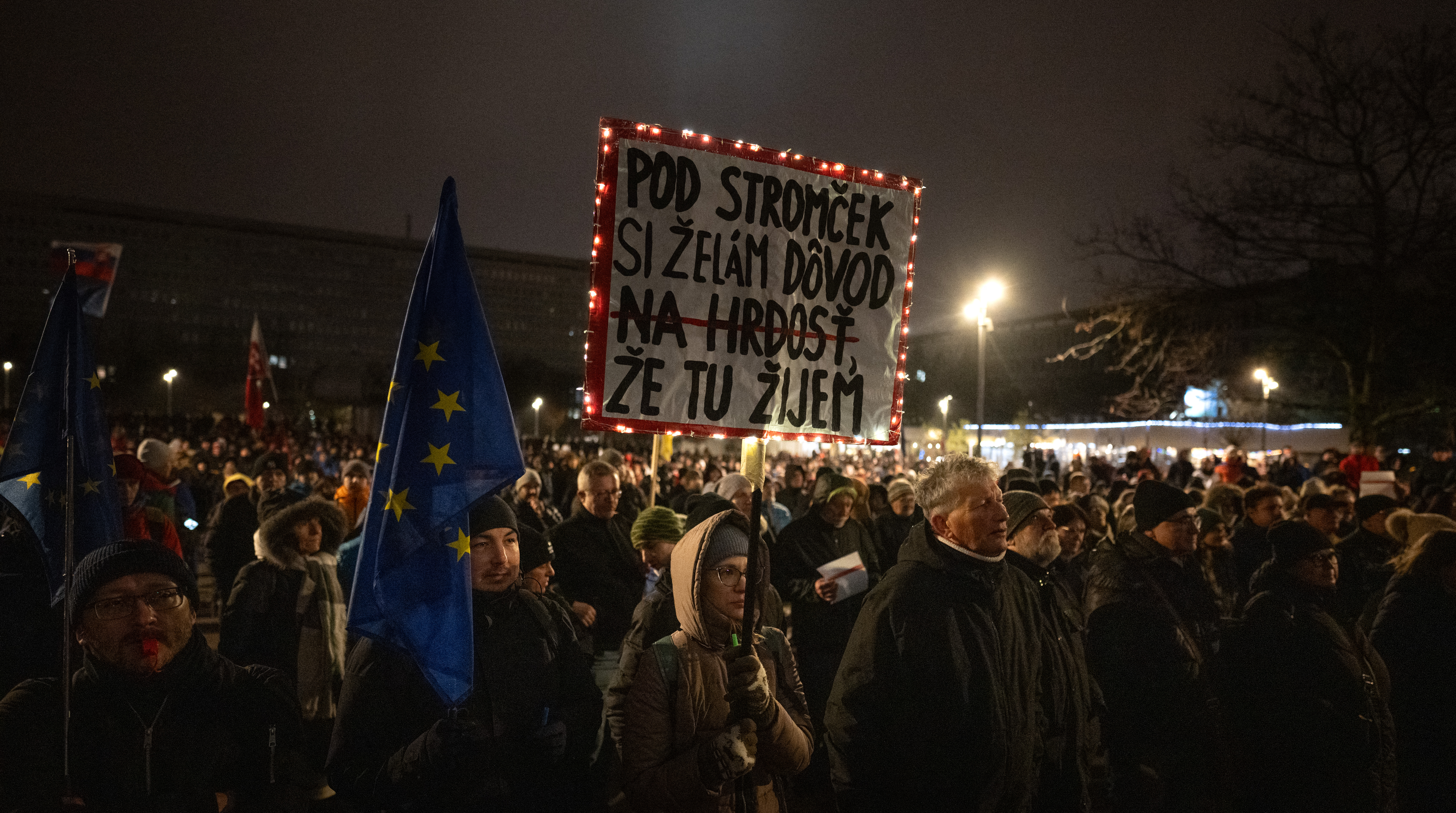 A protester holds a banner reading "For Christmas I wish to get a reason to be proud that I live here" as demonstrators gather for a protest against the abolition of the whistleblower protection office and penal code changes in Bratislava, Slovakia on December 15, 2025.