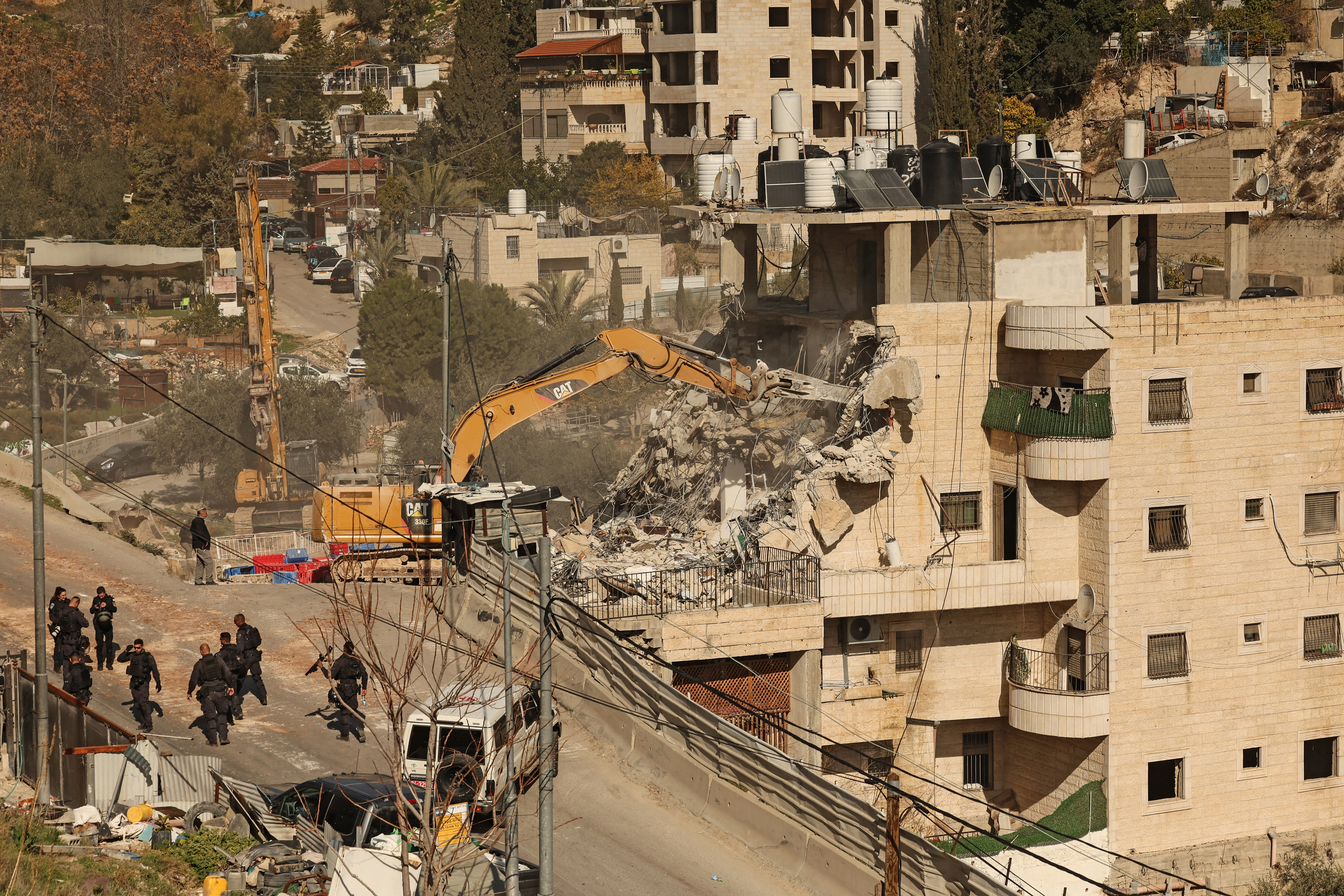 Israeli forces gather as excavators demolish a building constructed without a permit in the Wadi Qaddum area near the Silwan neighbourhood of east Jerusalem on December 22, 2025.