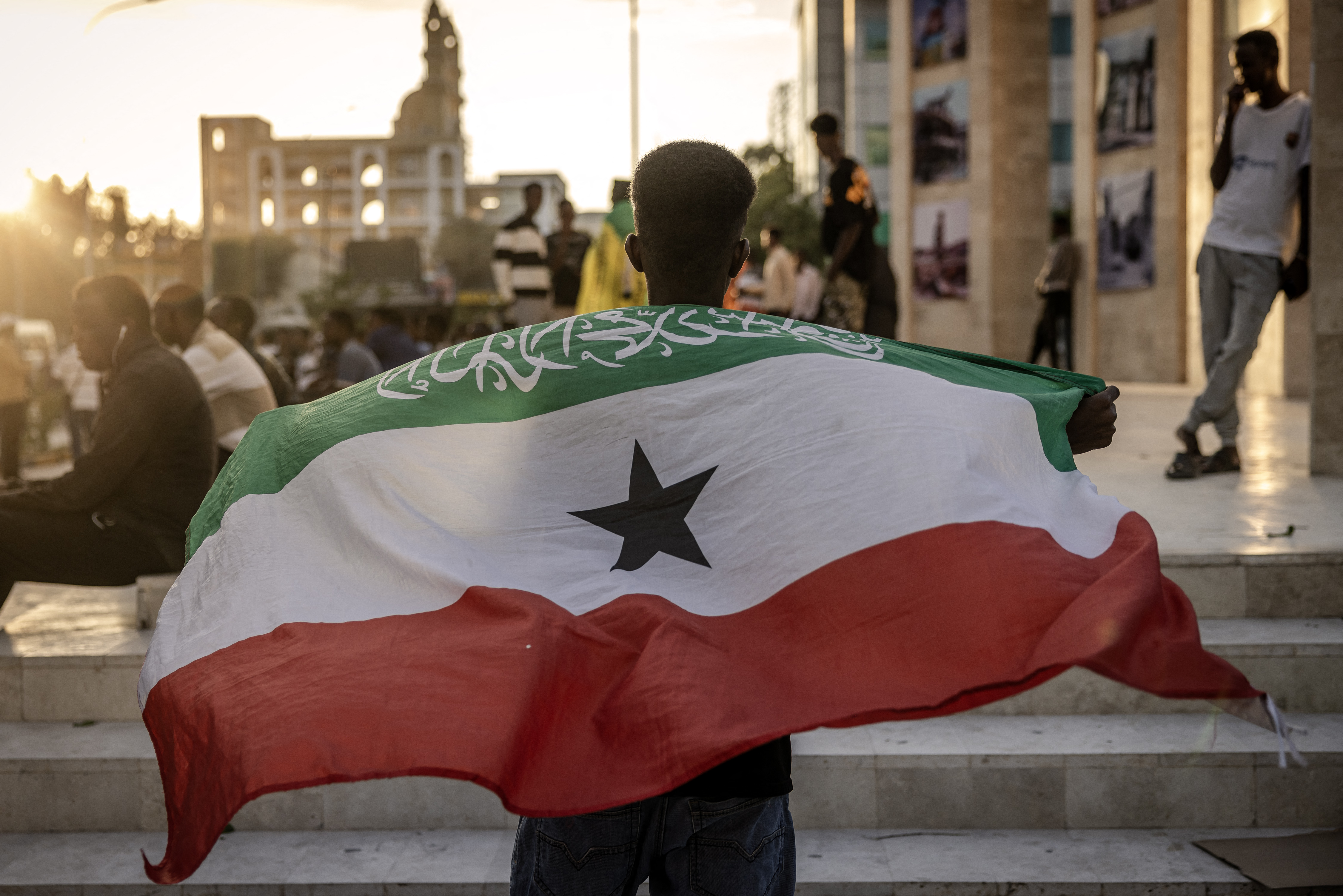 A man holds a flag of Somaliland in front of the Hargeisa War Memorial monument.
