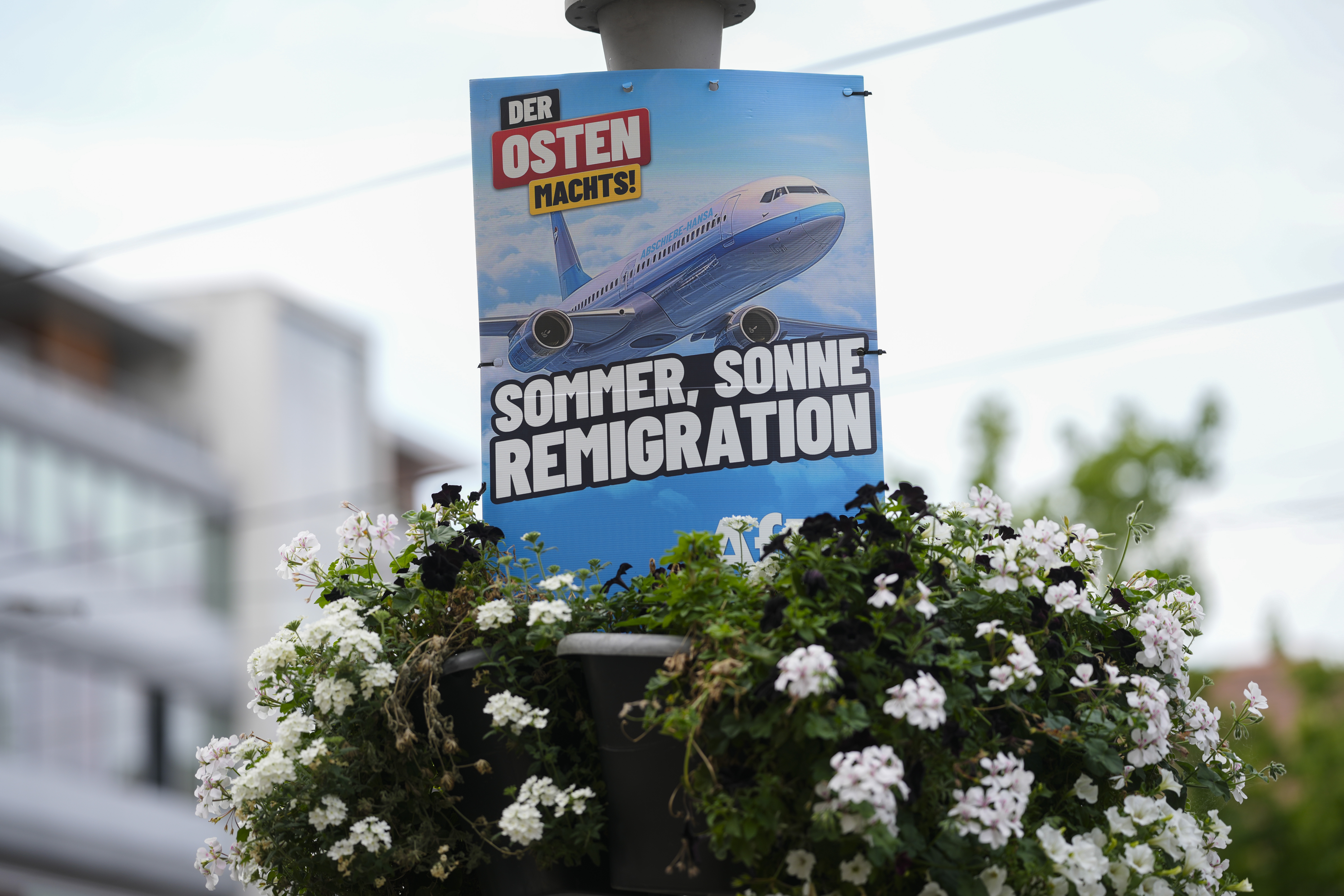 An electoral poster for the far-right Alternative for Germany, or And, using the slogan, "Summer, Sun, Remigration," and depicting a plane dubbed "Deportation Airline", is displayed in the capital of German federal state Thuringia, in Erfurt, Germany, Wednesday, Aug. 14, 2024. In the federal state Thuringia, in former East Germany, the citizens are called to vote for a new state parliament on Sept. 1, 2024. (AP Photo/Markus Schreiber)