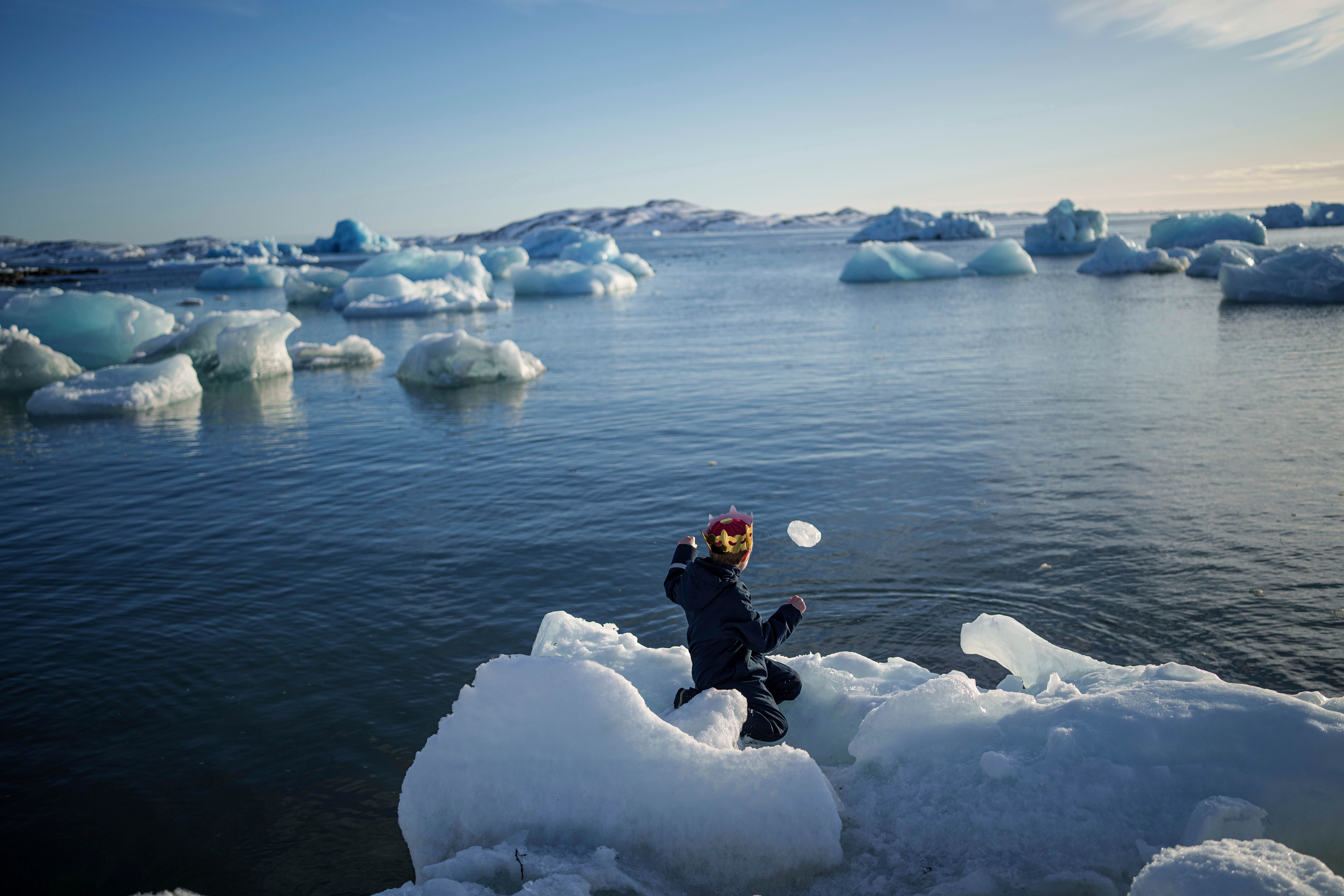 A boy throws ice into the sea.