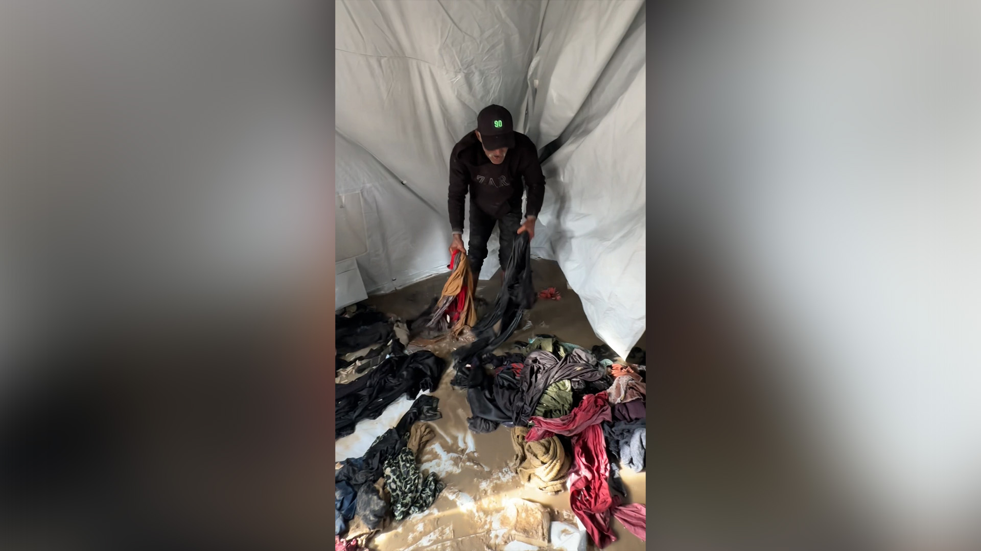 Displaced Palestinian Basim Abu Muhareb sorts through his family's waterlogged belongings after floods from Storm Byron in Deir el-Balah, Gaza on December 12, 2025. [Al Jazeera]