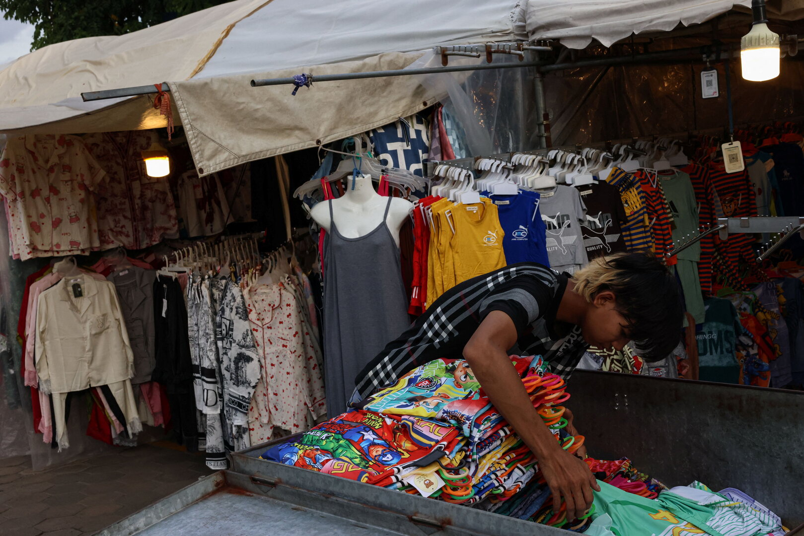 A clothes vendor organizes merchandise to prepare for business at a market in Phnom Penh, Cambodia, Aug. 1, 2025. [Tyrone Siu/Reuters]