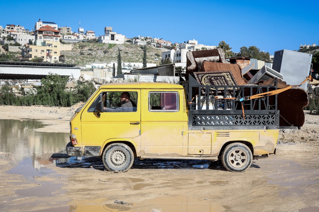 A man drives a pick-up truck loaded with furniture from his about-to-be demolished home.