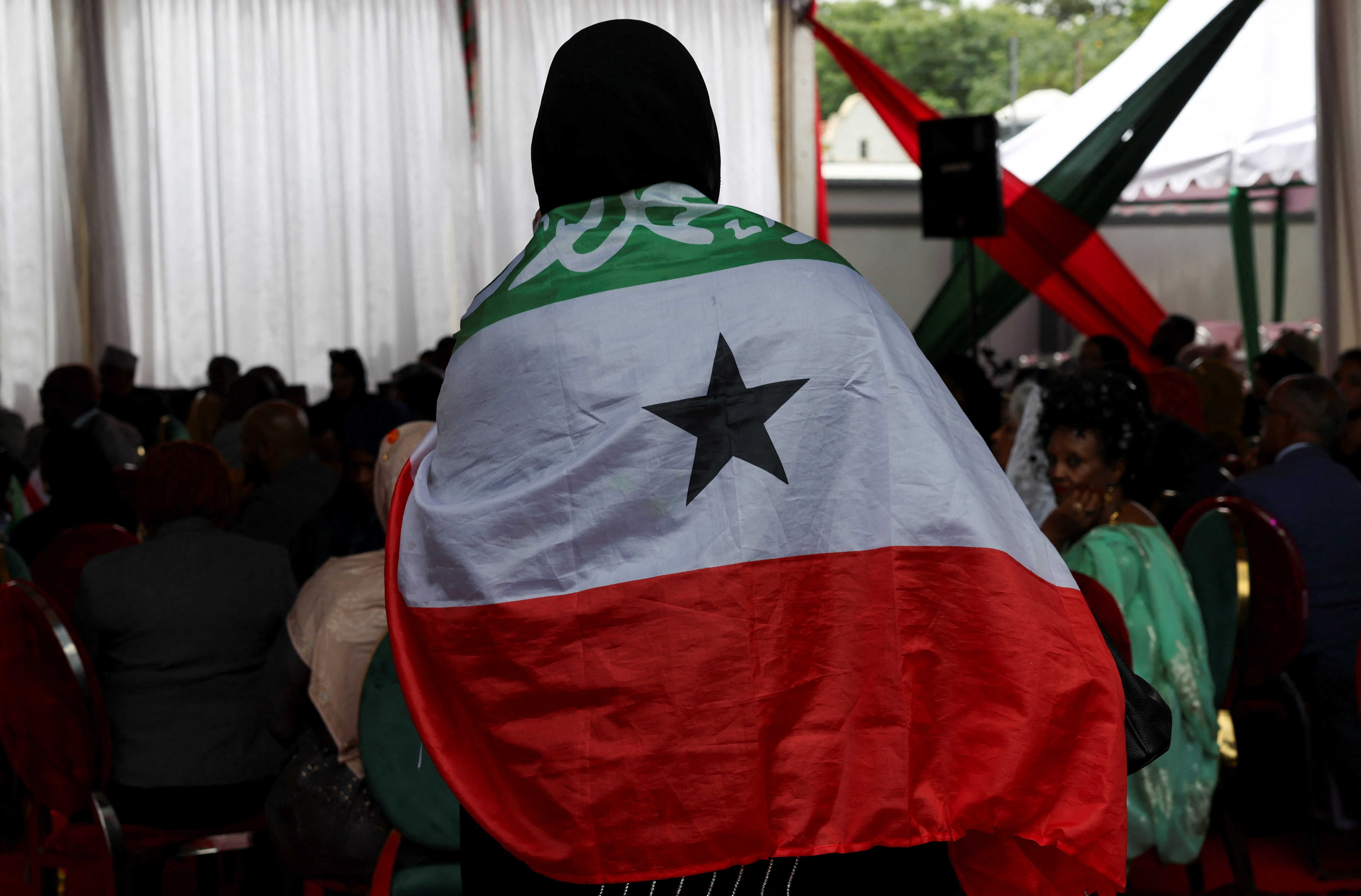 A delegate wrapped in the flag of Somaliland arrives for the unveiling of the Somaliland Mission premises, in Nairobi