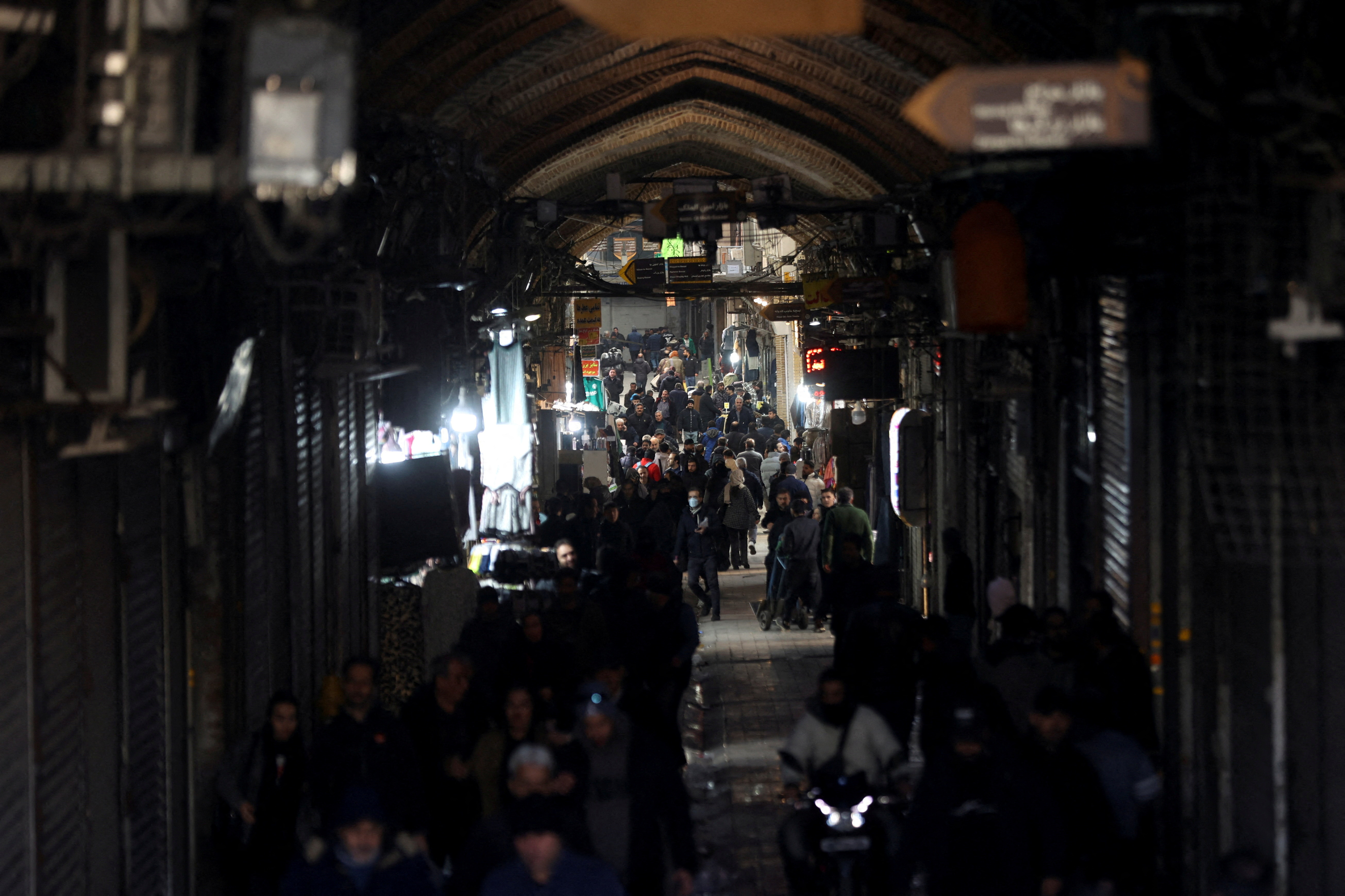 People walk past closed shops, following protests over a plunge in the currency's value, in the Tehran Grand Bazaar