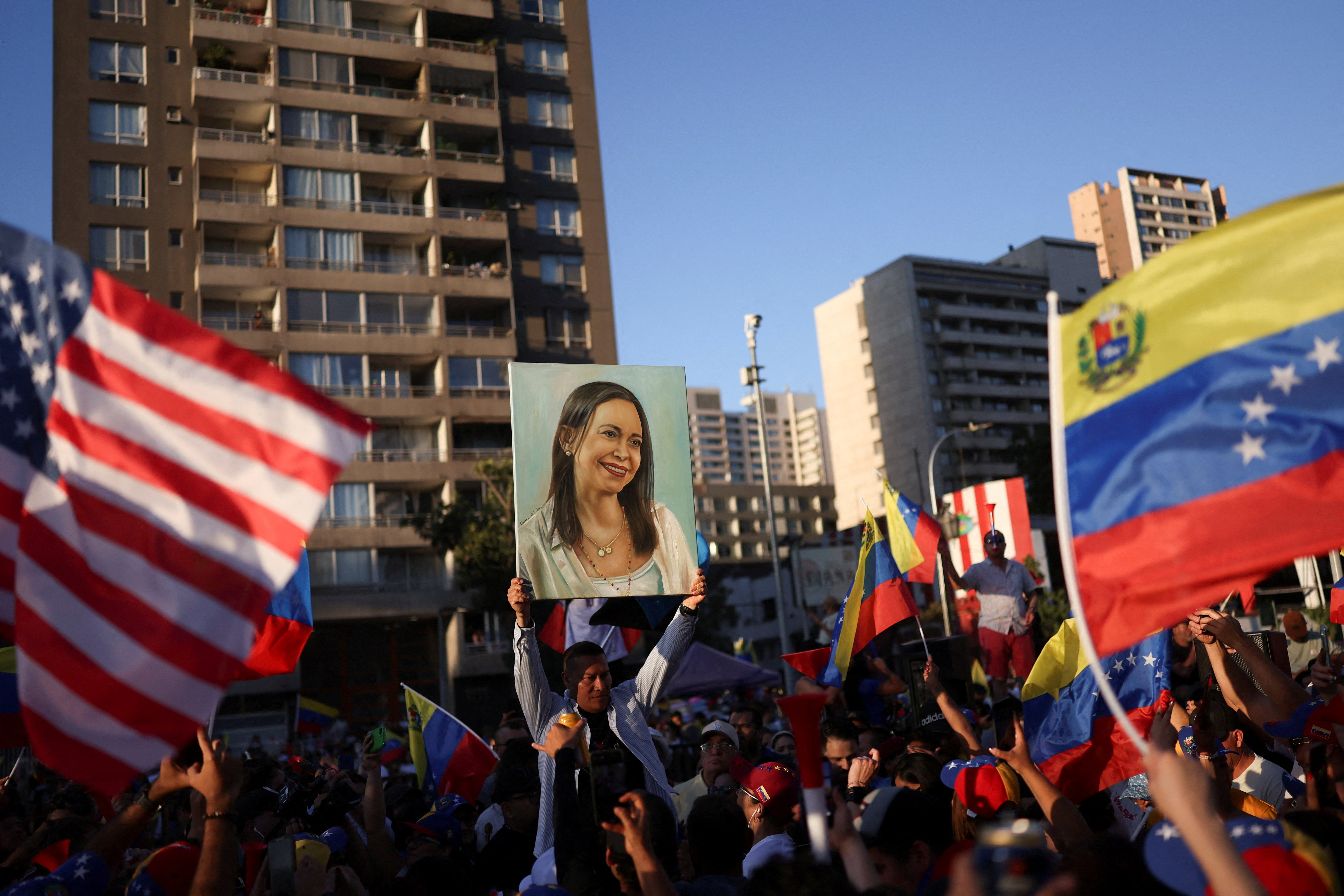 Protesters hold up an image of Maria Corina Machado