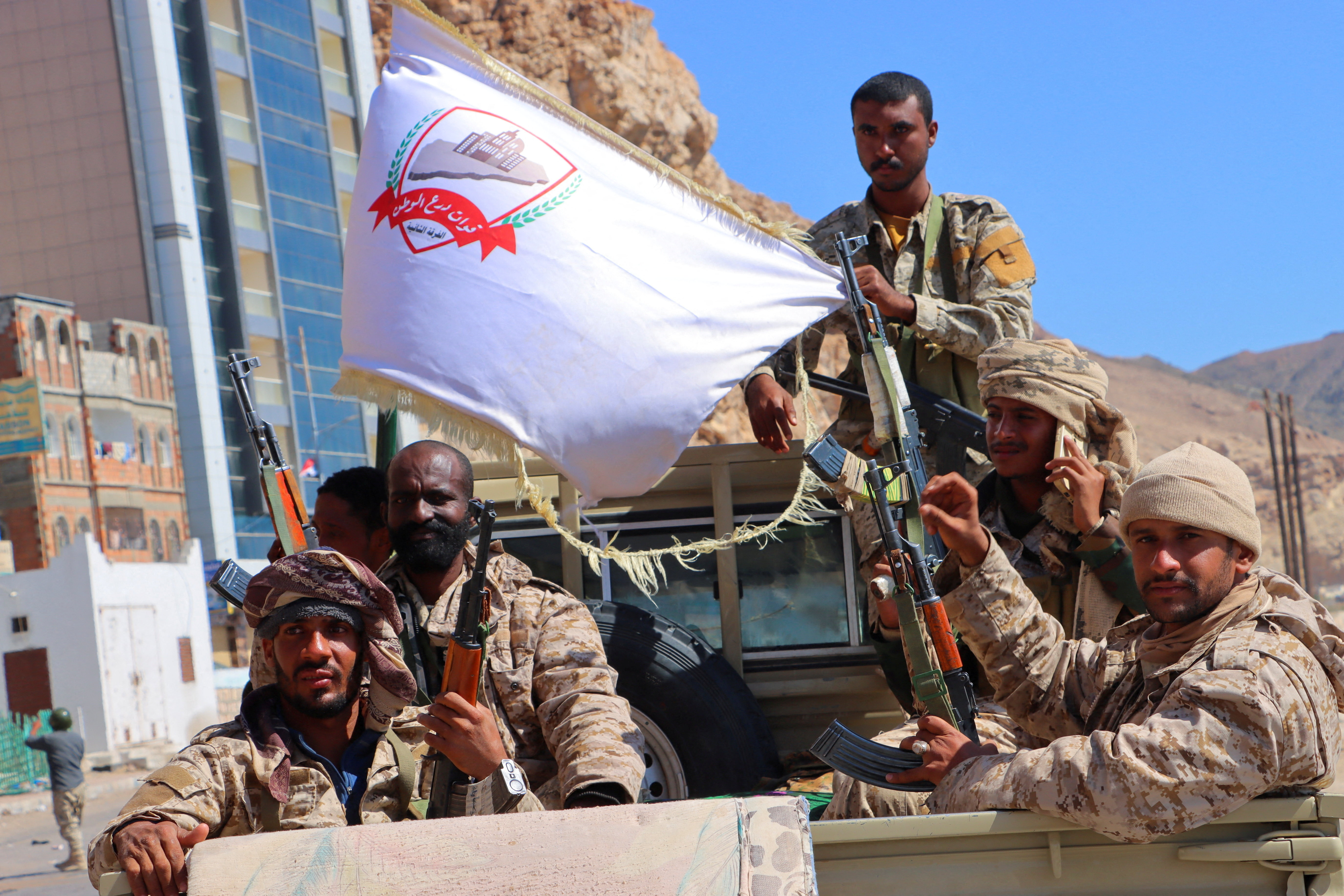 Government soldiers ride on the back of a pick-up truck.