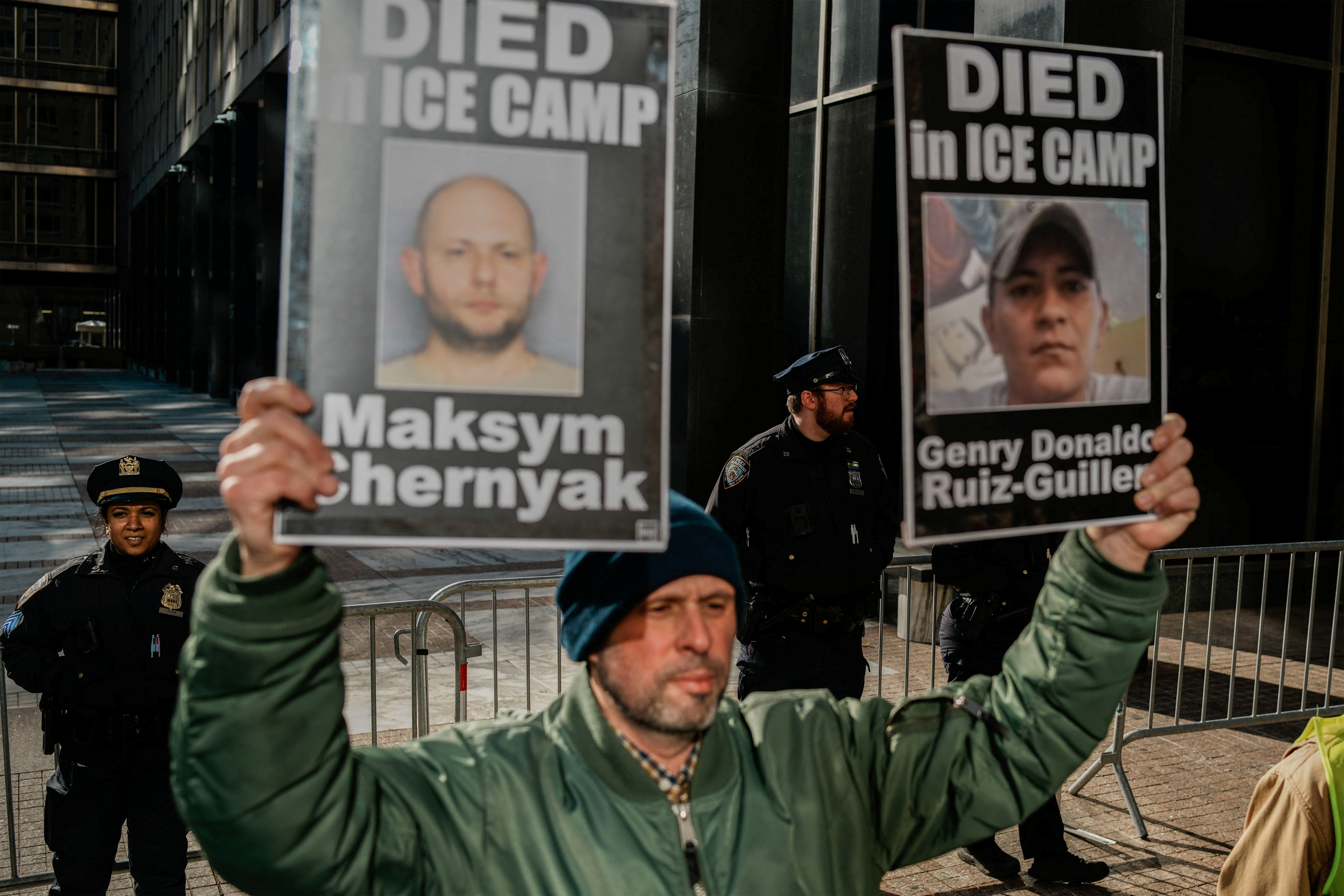 A protester holds up two signs showing people who died in ICE custody