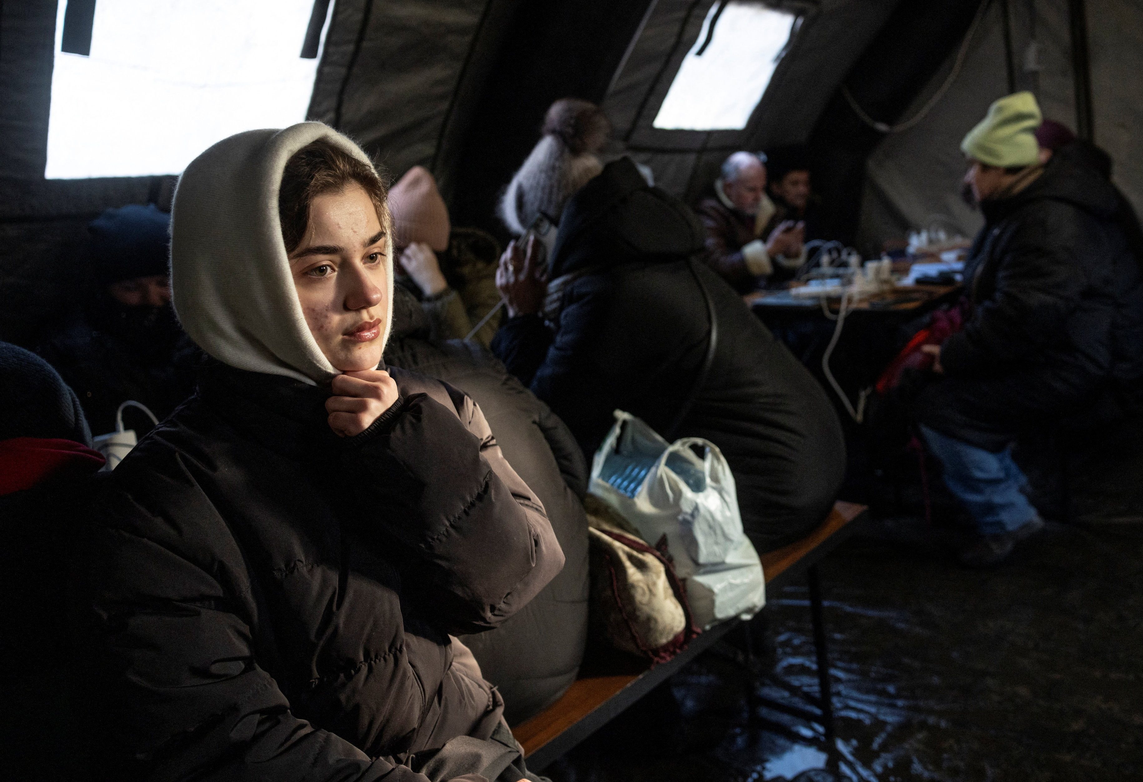 People warm up in a tent provided by emergency services for residents whose apartments are left without heating during sub-zero temperatures following Russian missile and drone strikes on civilian infrastructure, amid Russia's attack on Ukraine, on a winter day in Kyiv, Ukraine January 20, 2026. REUTERS/Thomas Peter