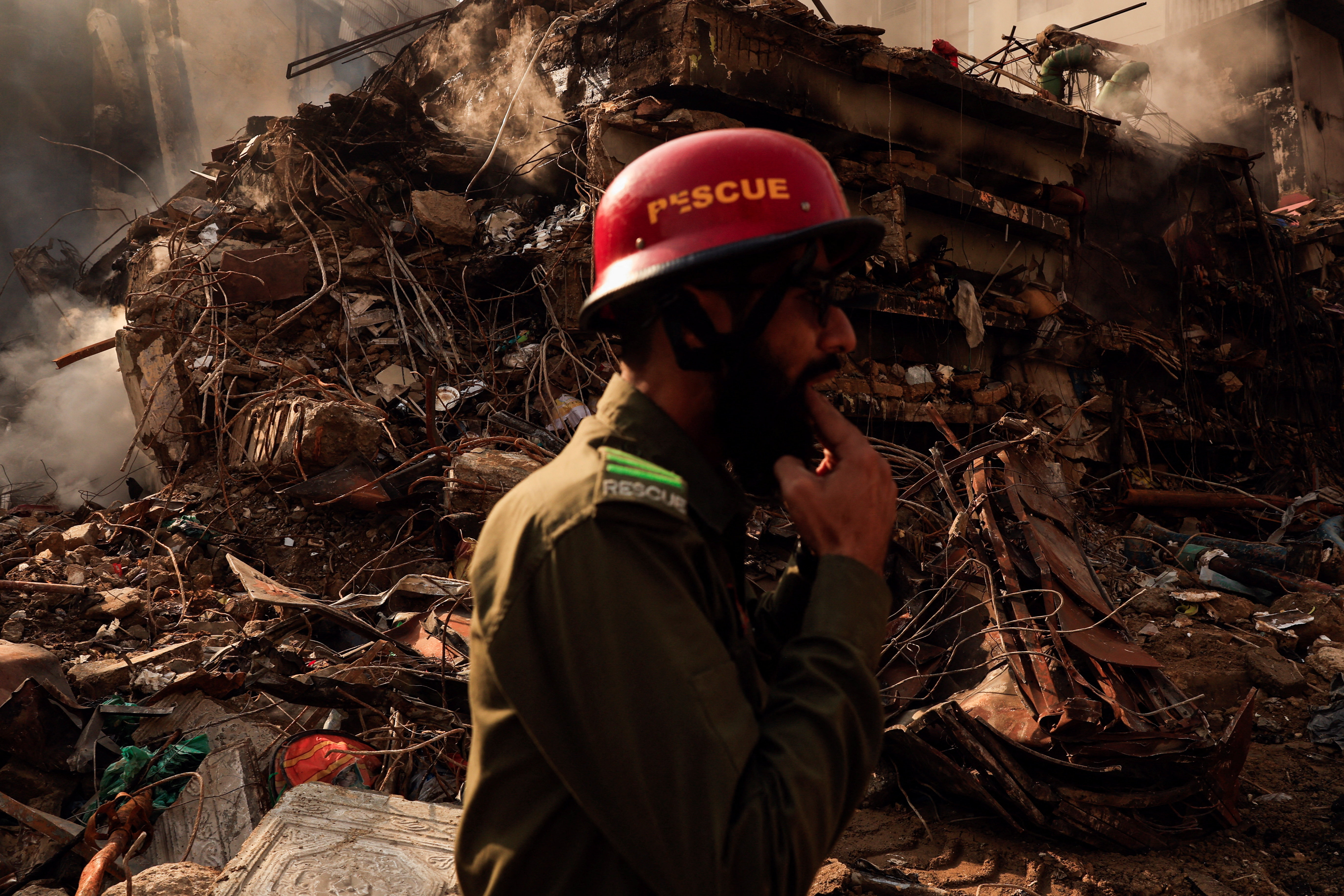 A rescue worker whistles to call his team member (not pictured) as he walks past the collapsed floors, following a massive fire that broke out at the Gul Plaza Shopping Mall, in Karachi