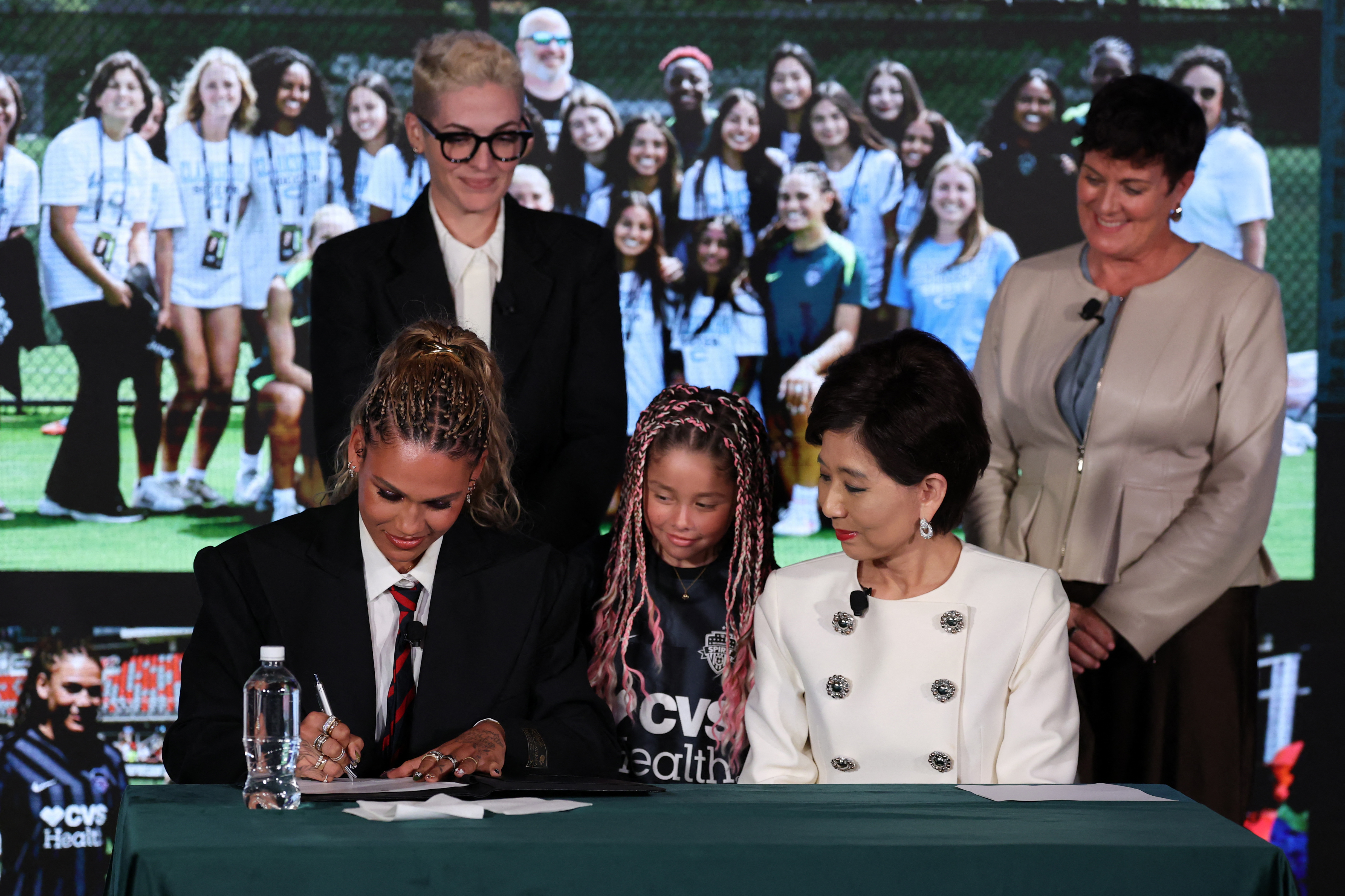 Trinity Rodman (front left) of the Washington Spirit signs a contract extention during a press conference at BMO Stadium
